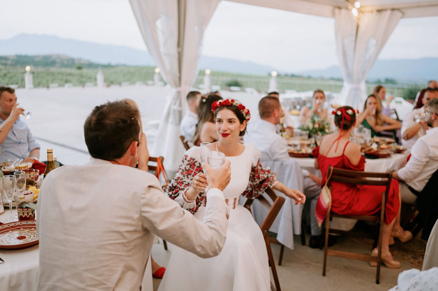 Wedding celebration toast moment under white tent with scenic mountain views.