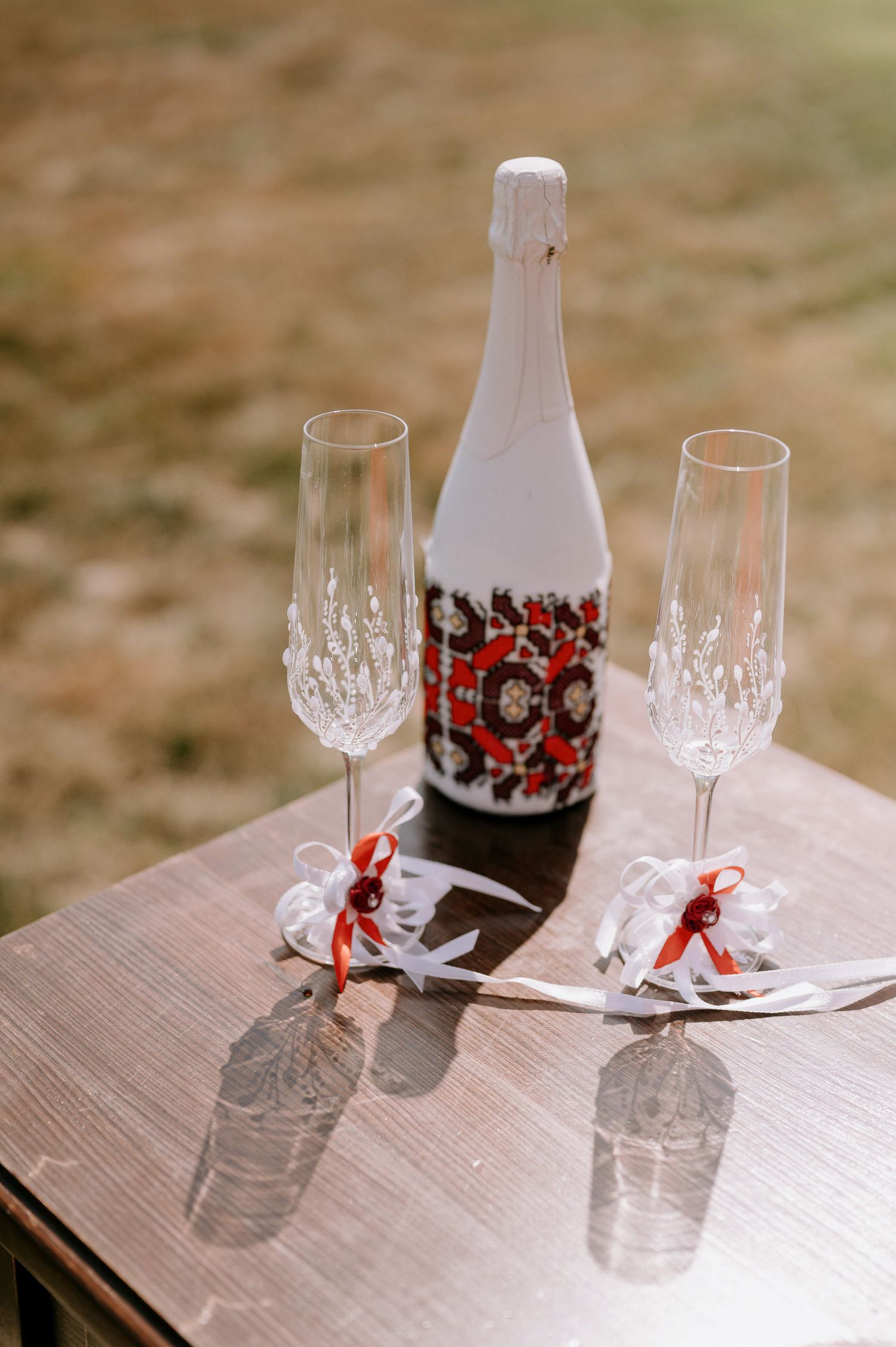 Elegant champagne bottle and crystal glasses arranged on wooden table with red ribbons.