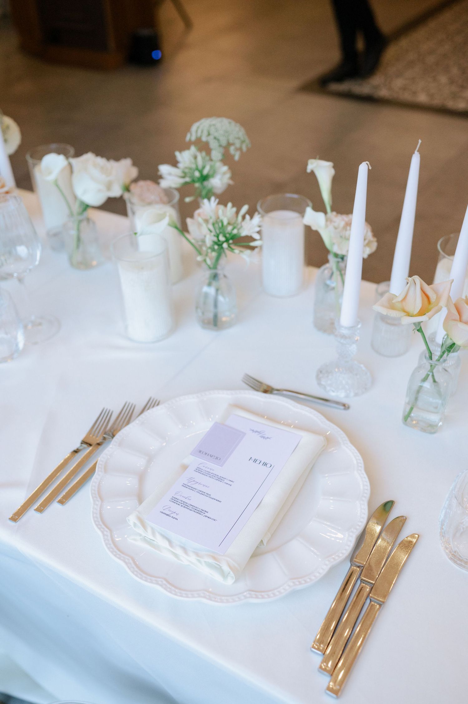 Elegant table setting with white linens, gold flatware, and delicate floral accents for an upscale event.