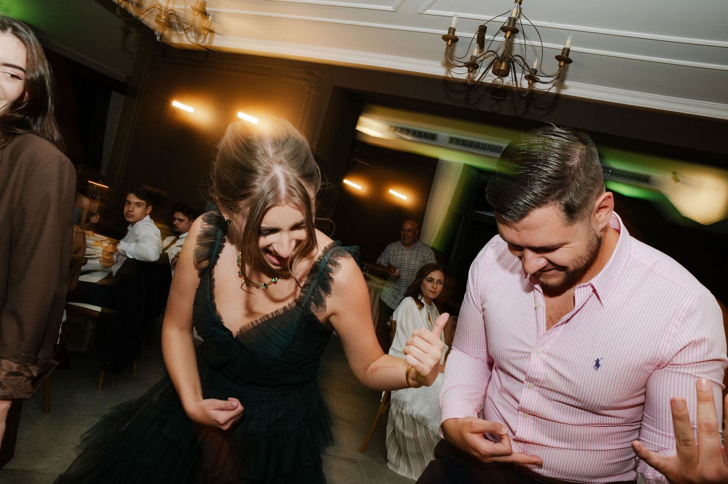 Wedding guests dancing and celebrating at a reception with pink and white decor.