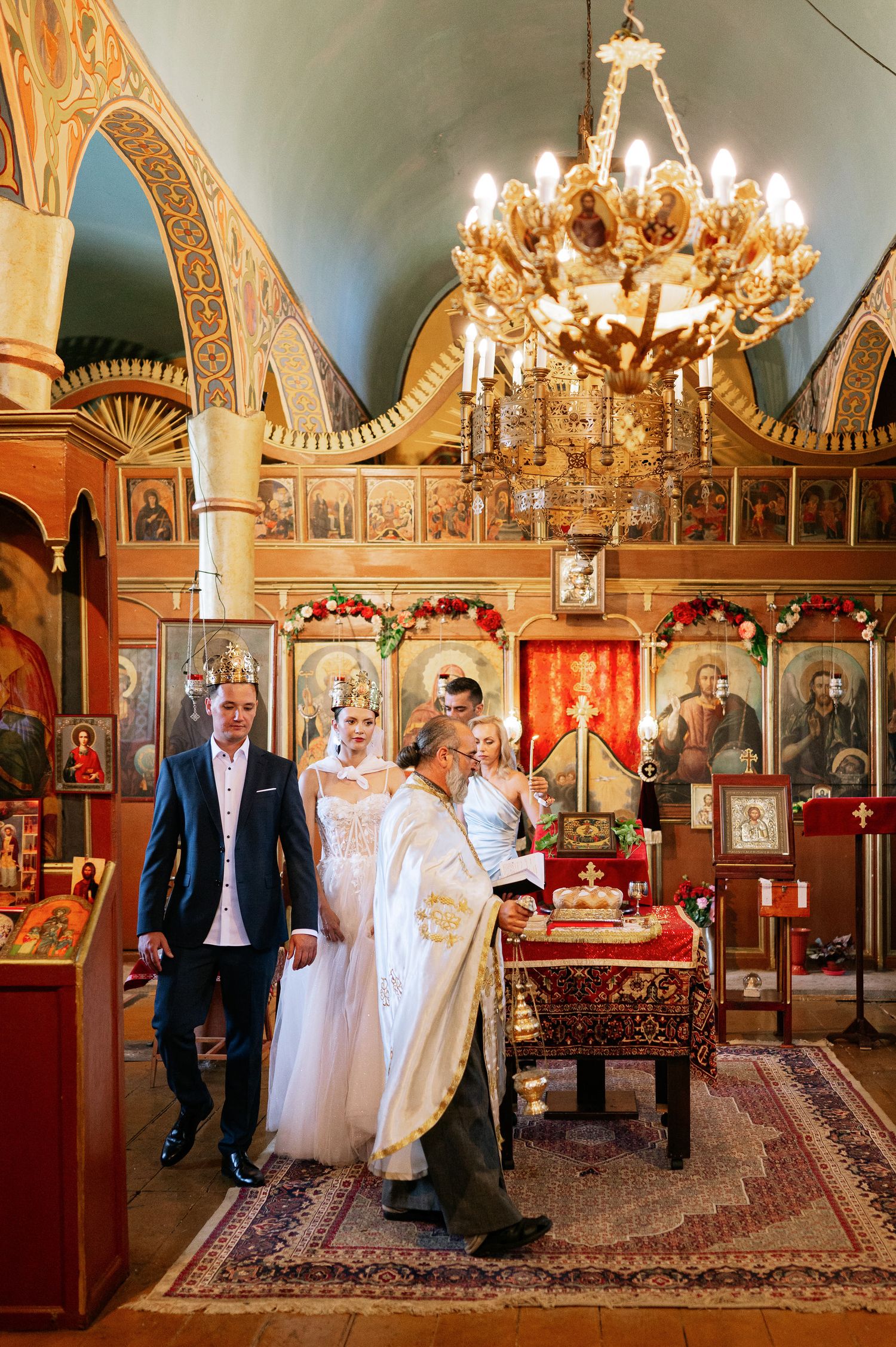 Orthodox church ceremony with elegant chandeliers and traditional religious decorations.
