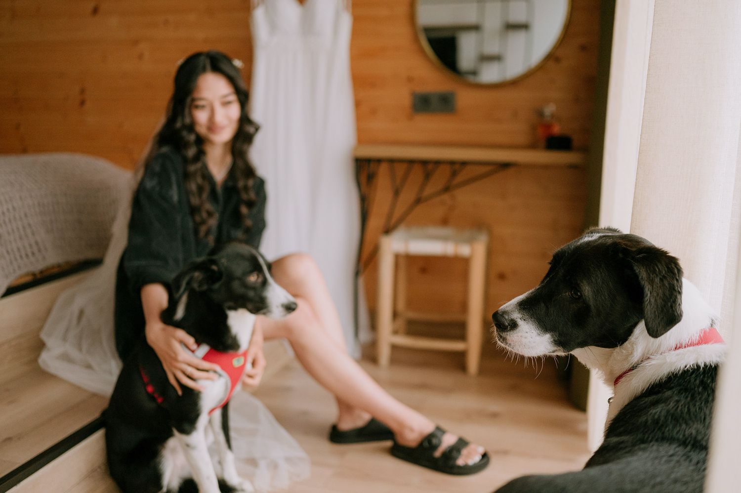 Relaxed indoor scene with someone in black clothing sitting near a displayed white dress.