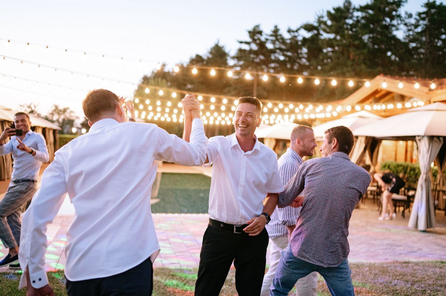 Guests enjoying a lively dance party under string lights at an outdoor venue.