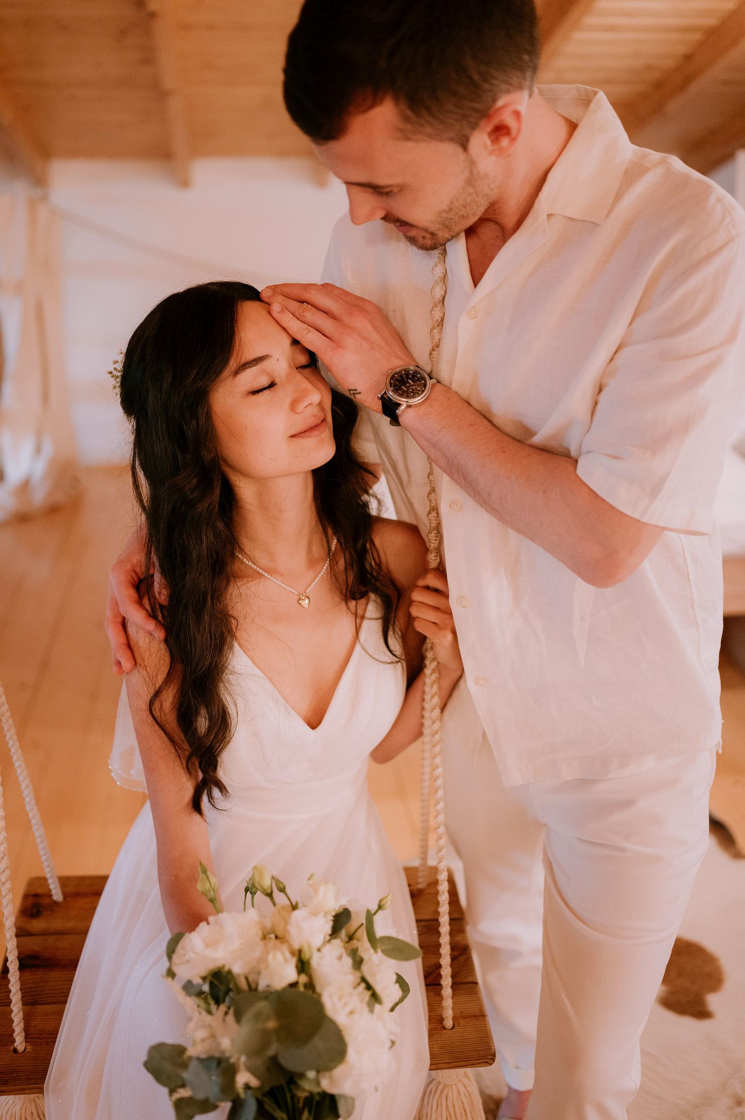 Intimate wedding moment captured in warm tones with rustic wooden backdrop.