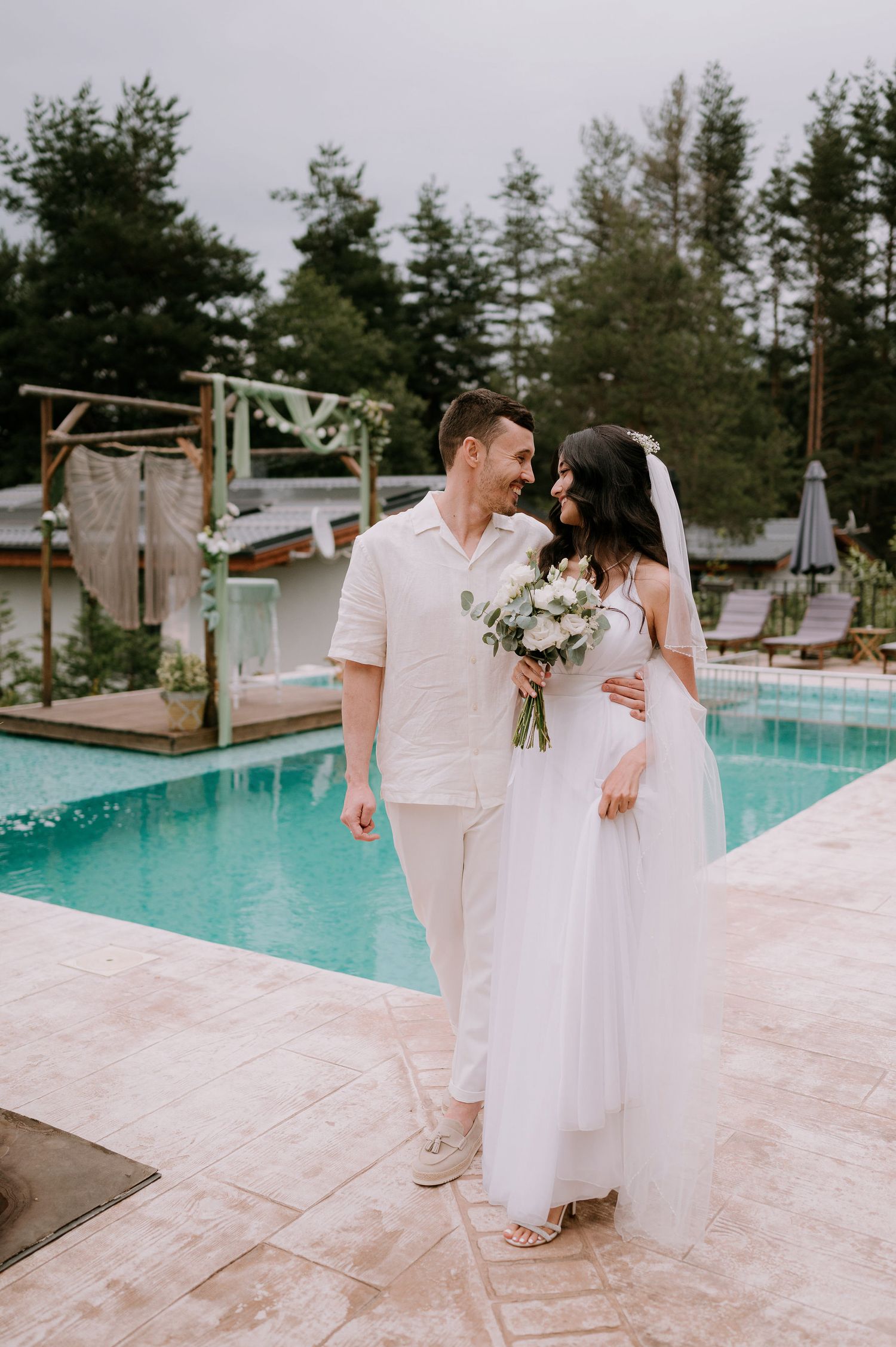 A bride and groom share intimate moments during their poolside wedding photoshoot.
