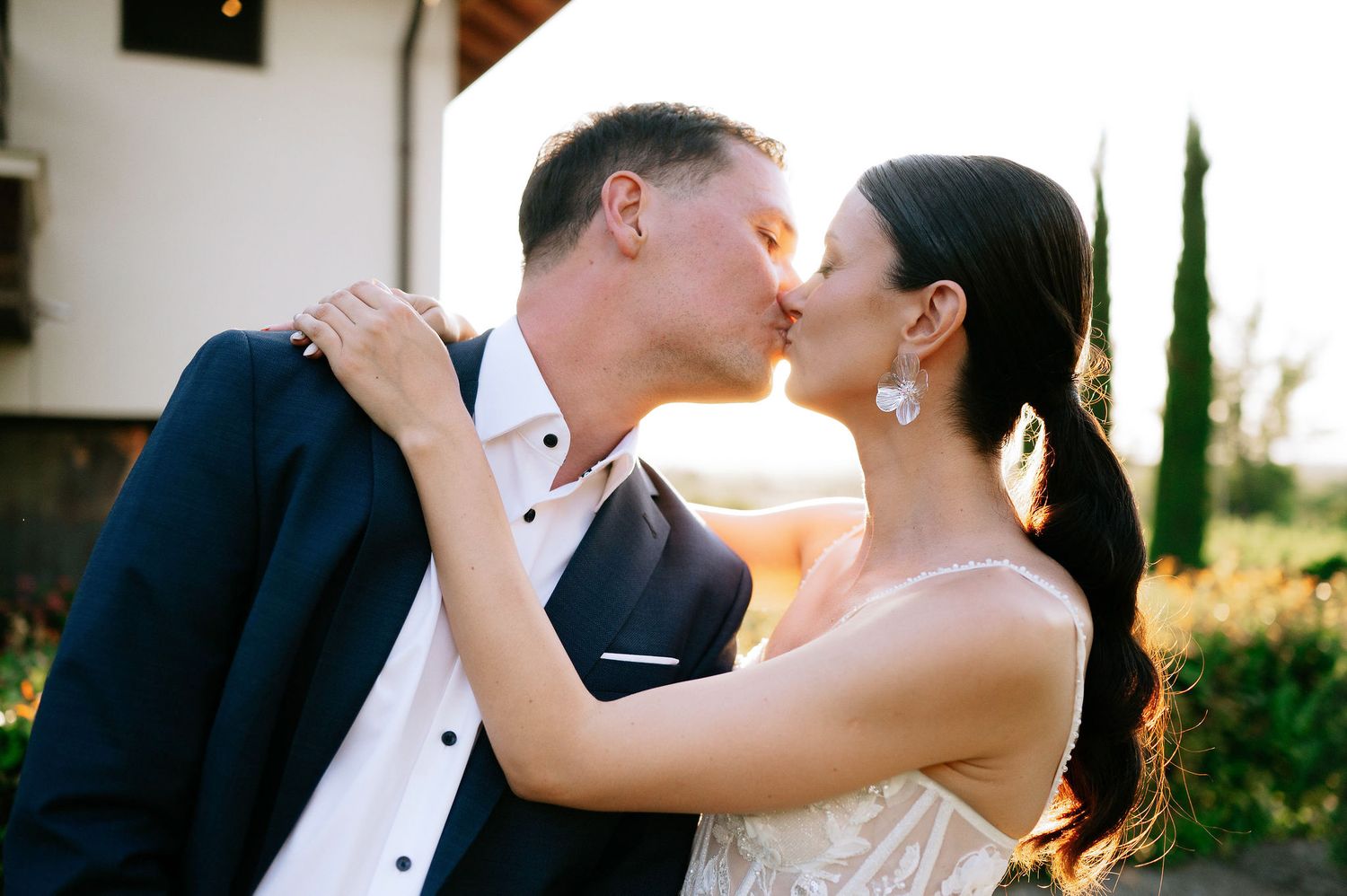 Romantic wedding portrait of couple dancing together at sunset with Mediterranean garden backdrop.