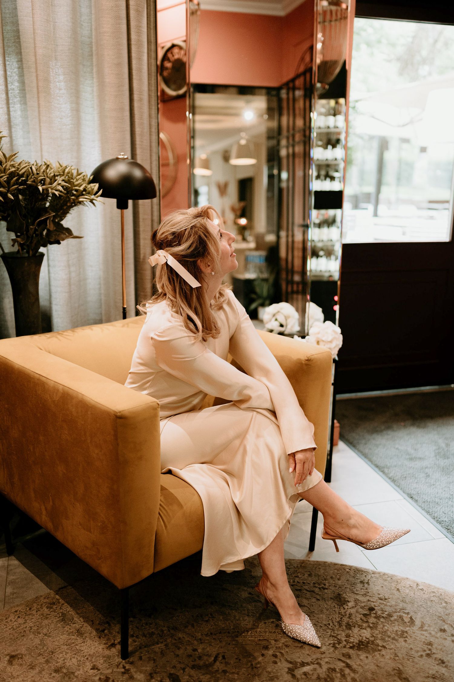 Person in cream dress relaxing on a brown leather couch in an elegant interior.
