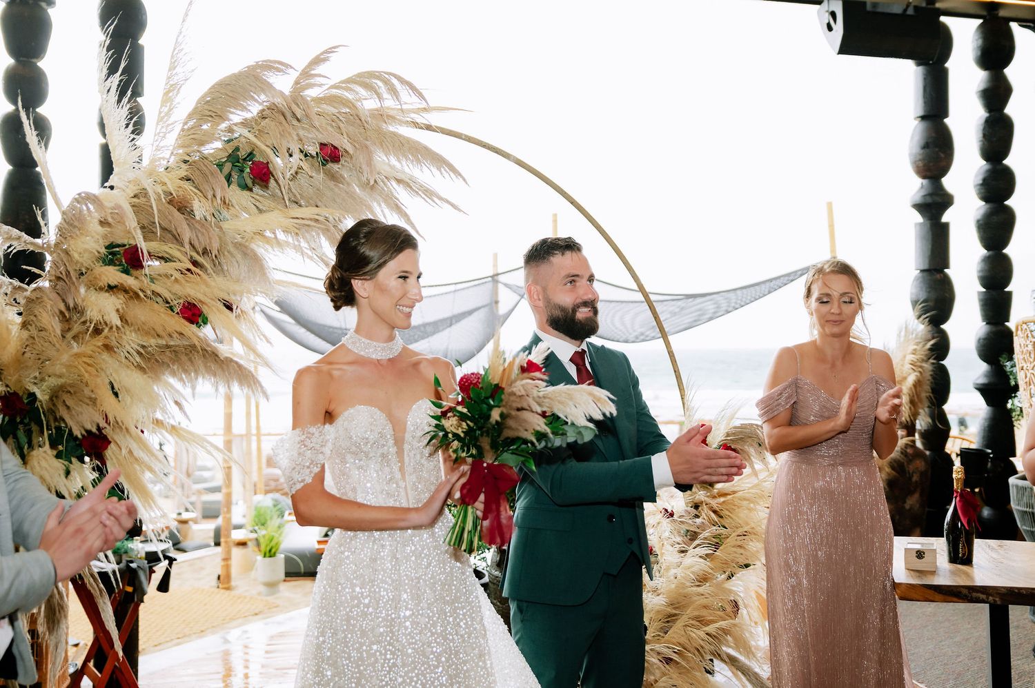 Wedding ceremony moment captured in a light-filled venue with boho-style dried floral arrangements.