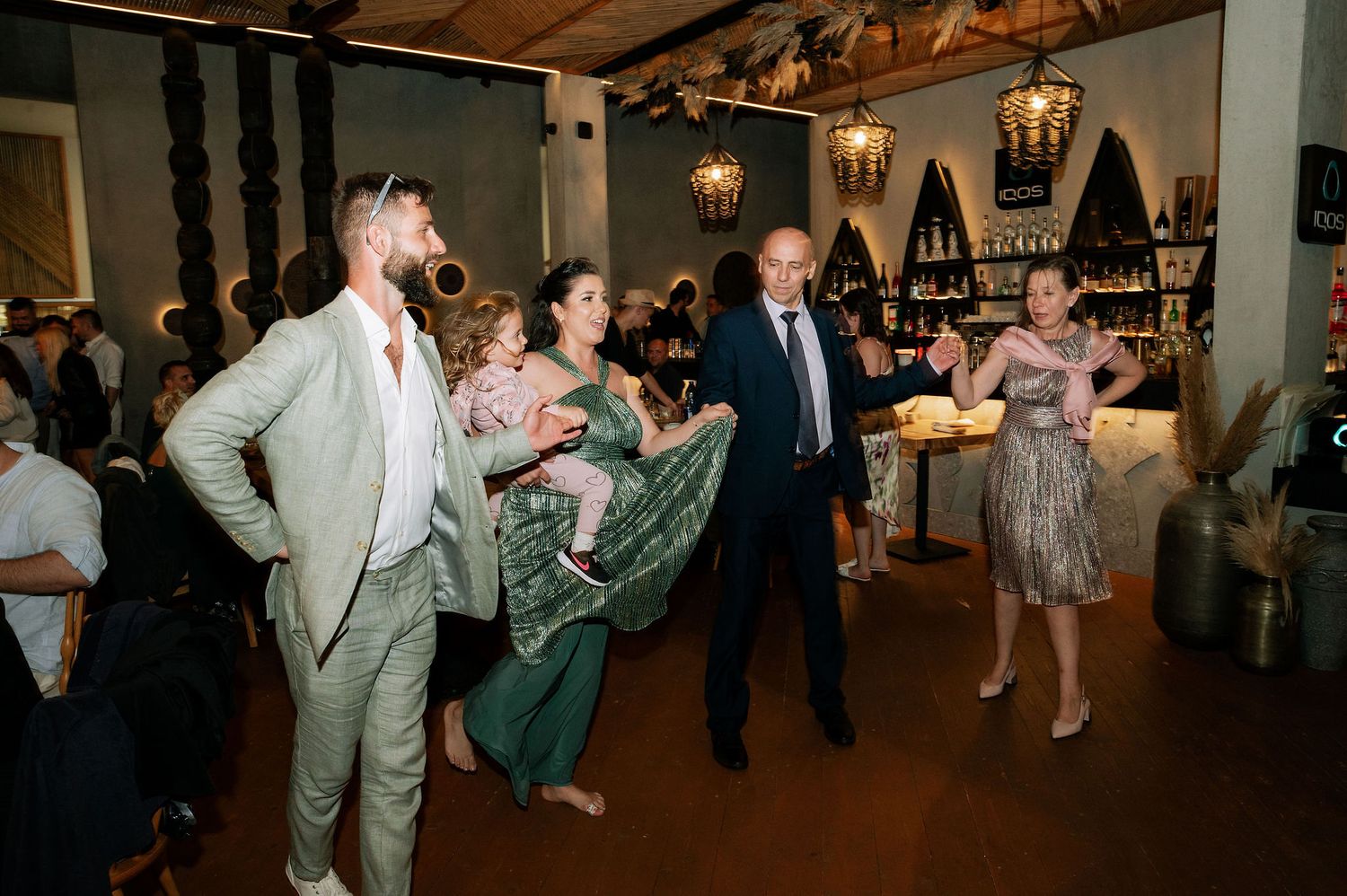 Large indoor wedding reception with guests dancing under wooden beam ceiling.