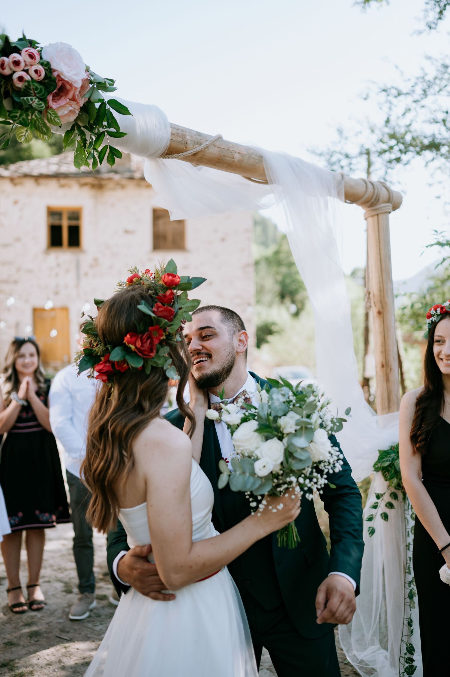 Romantic outdoor wedding moment captured against whitewashed walls and natural greenery.