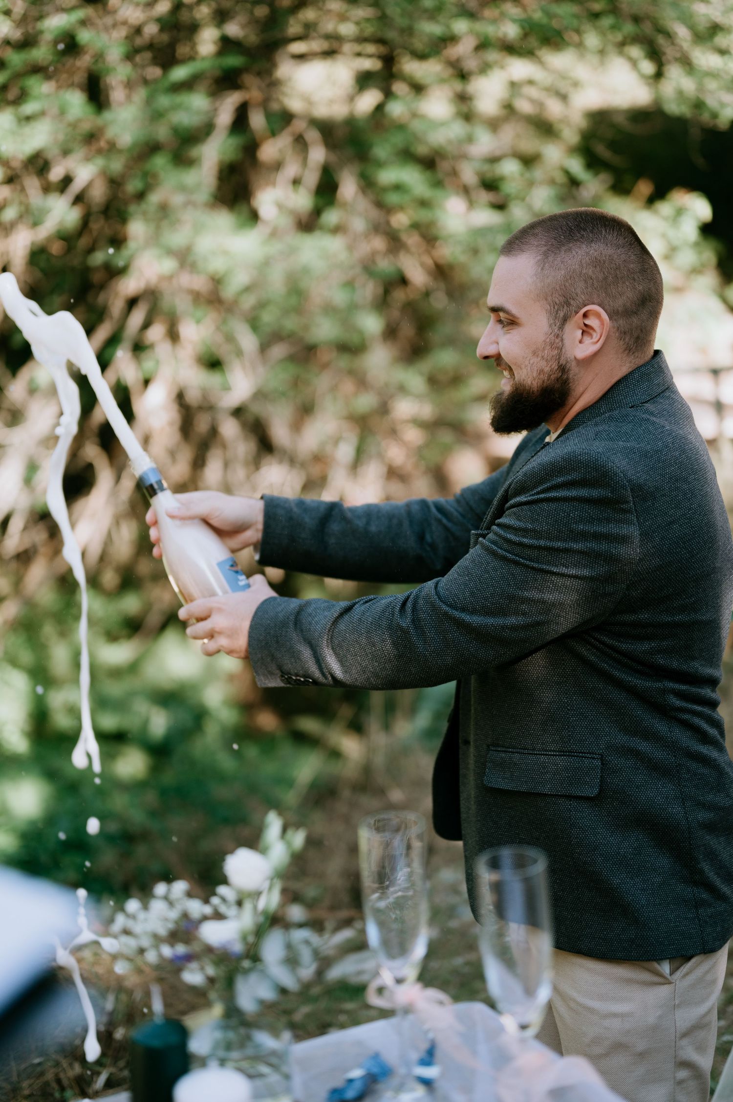 A person in a dark jacket pours champagne at an outdoor event.