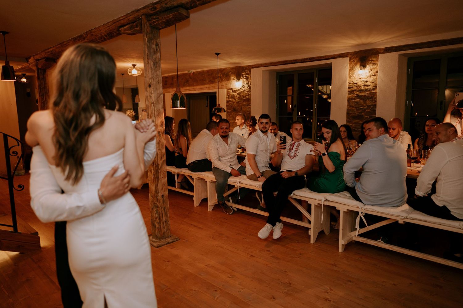 Dancers move gracefully across a wooden floor in a cozy brick-walled space.