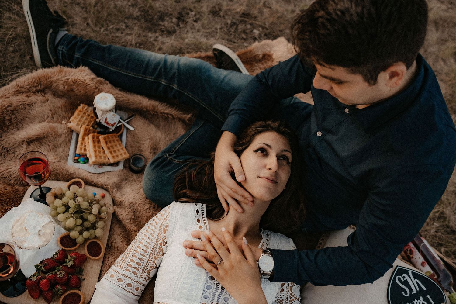 Couple enjoying an intimate picnic spread with wine and snacks overlooking mountain views.