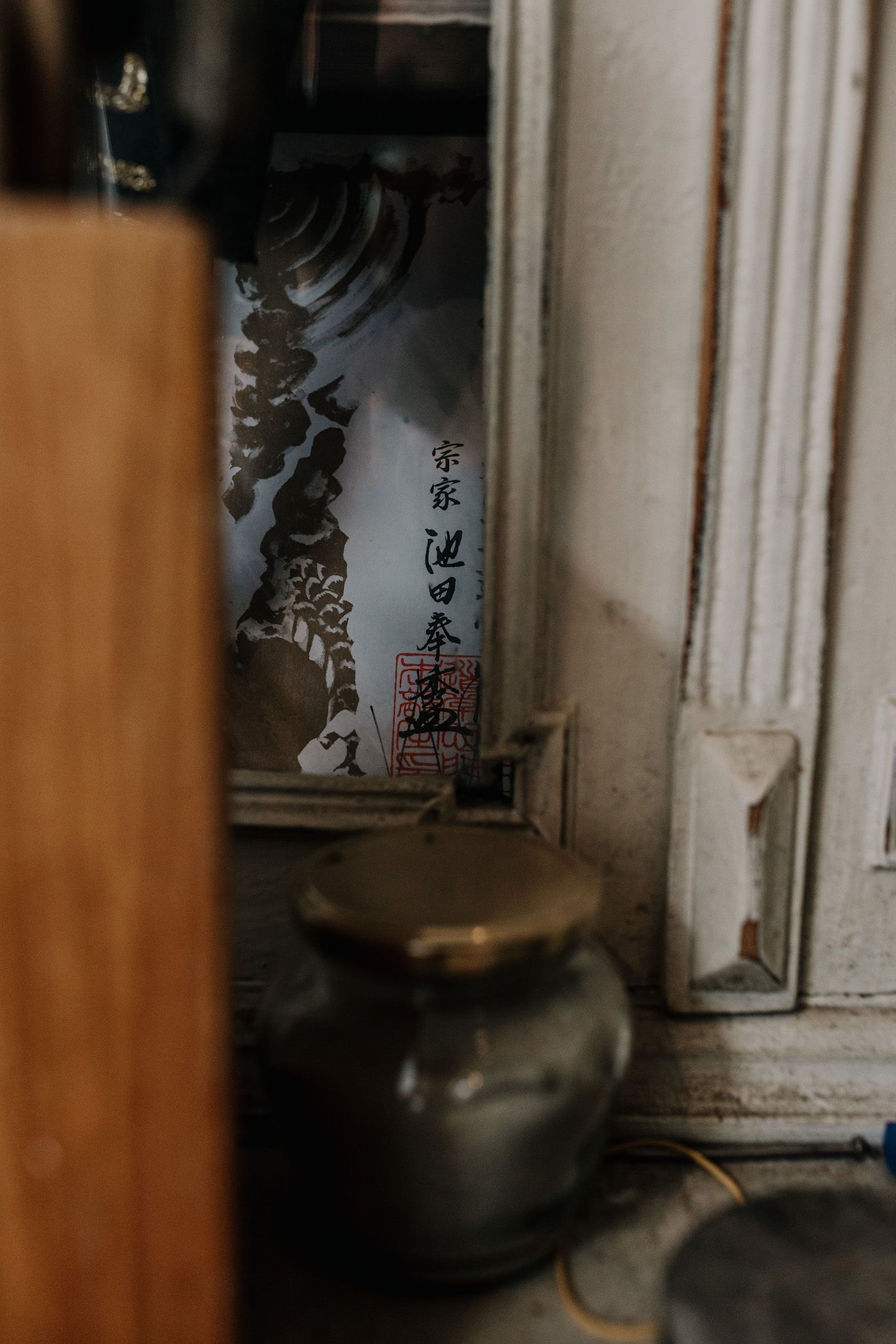 Vintage glass bottles and jars with Japanese characters arranged on wooden shelves in atmospheric lighting.