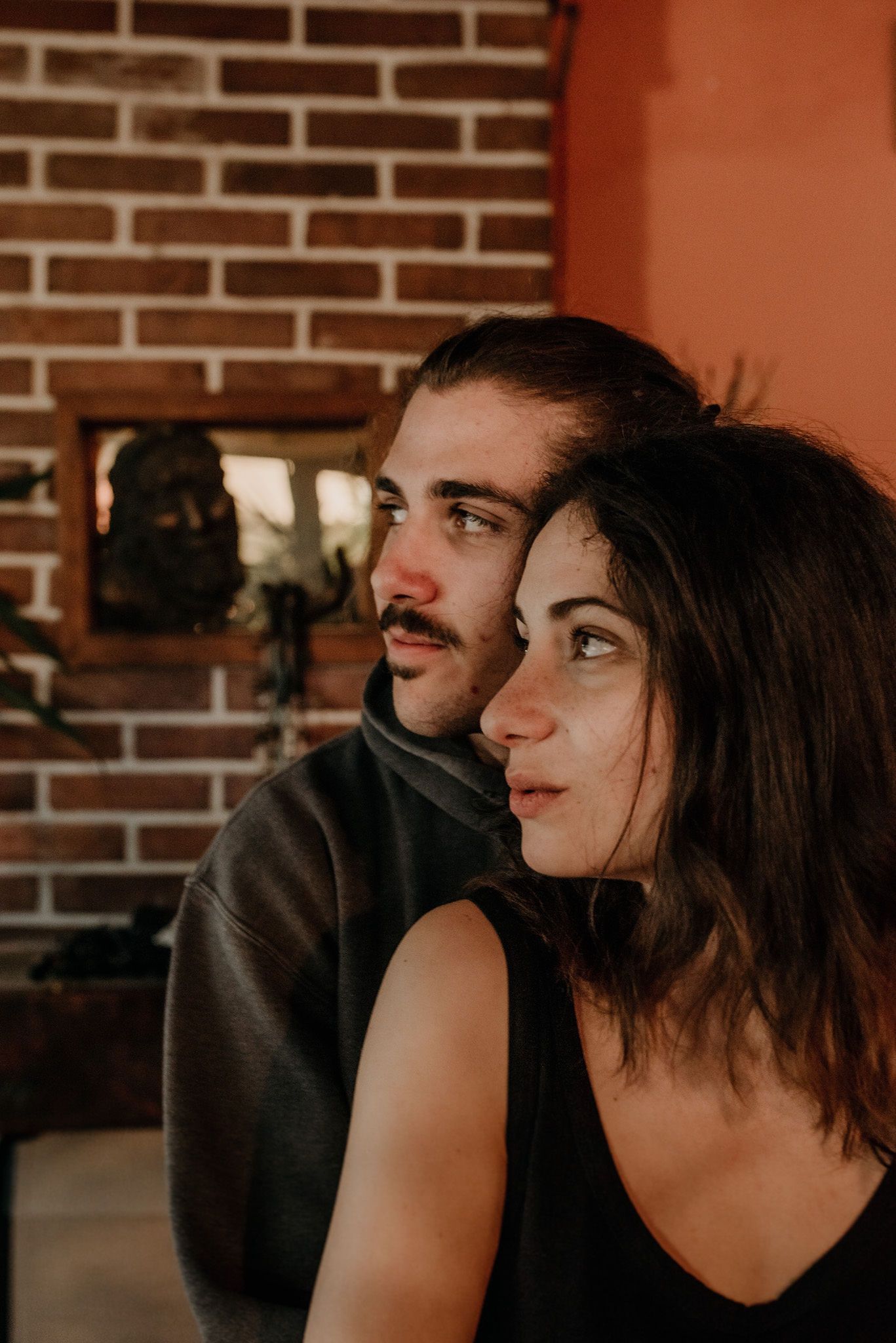A series of candid profile portraits showing intimate moments between a couple against a brick wall background.