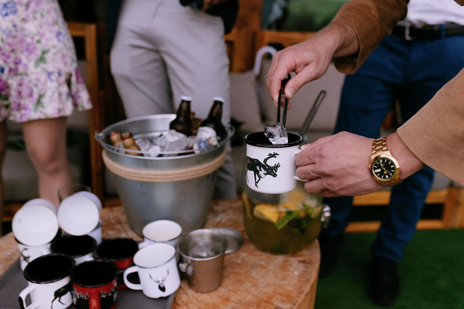 Rustic wooden table with coffee cups and drinks being served at an outdoor gathering.