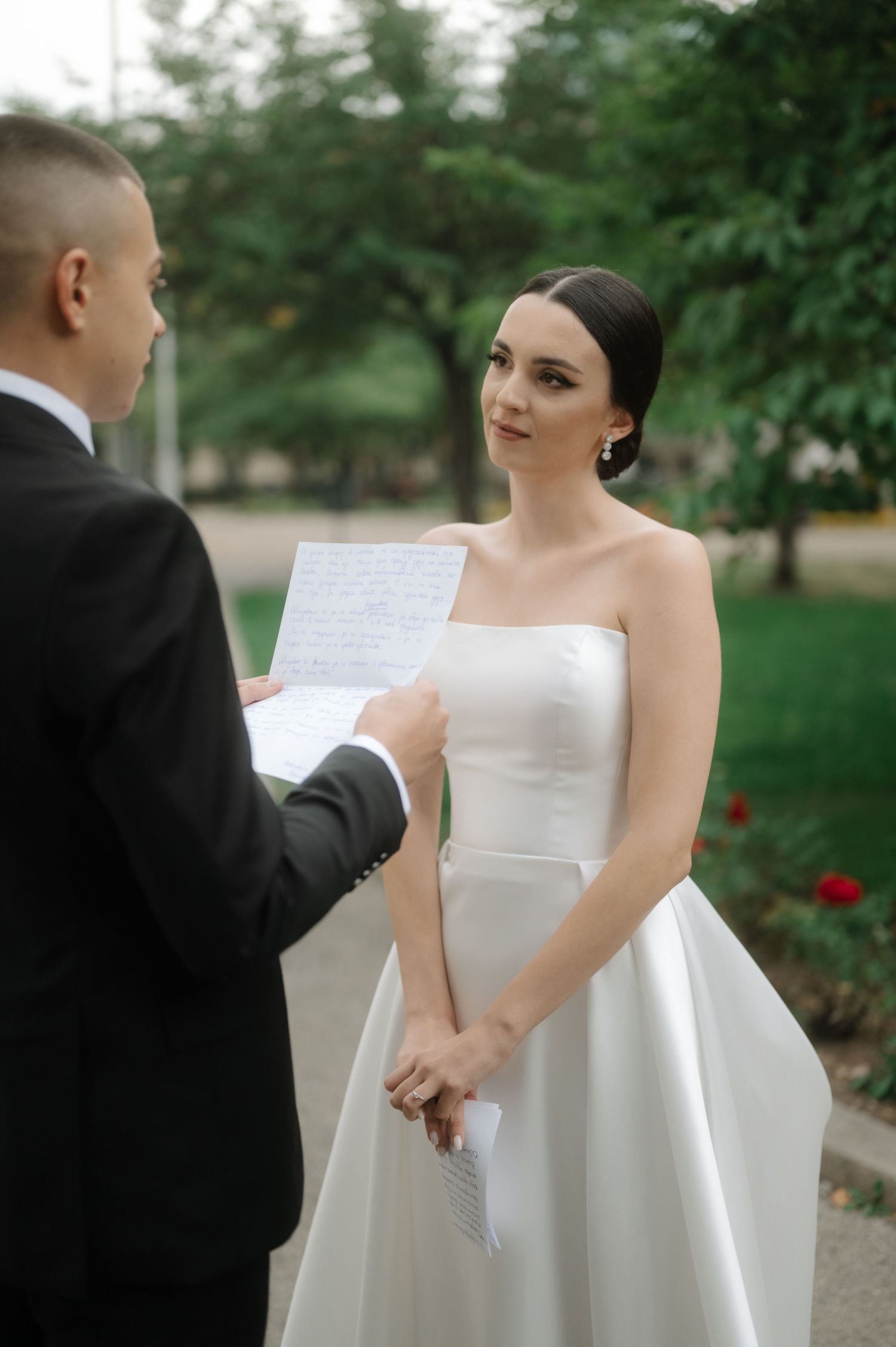 Bride and groom reading personal vows during an outdoor wedding ceremony.