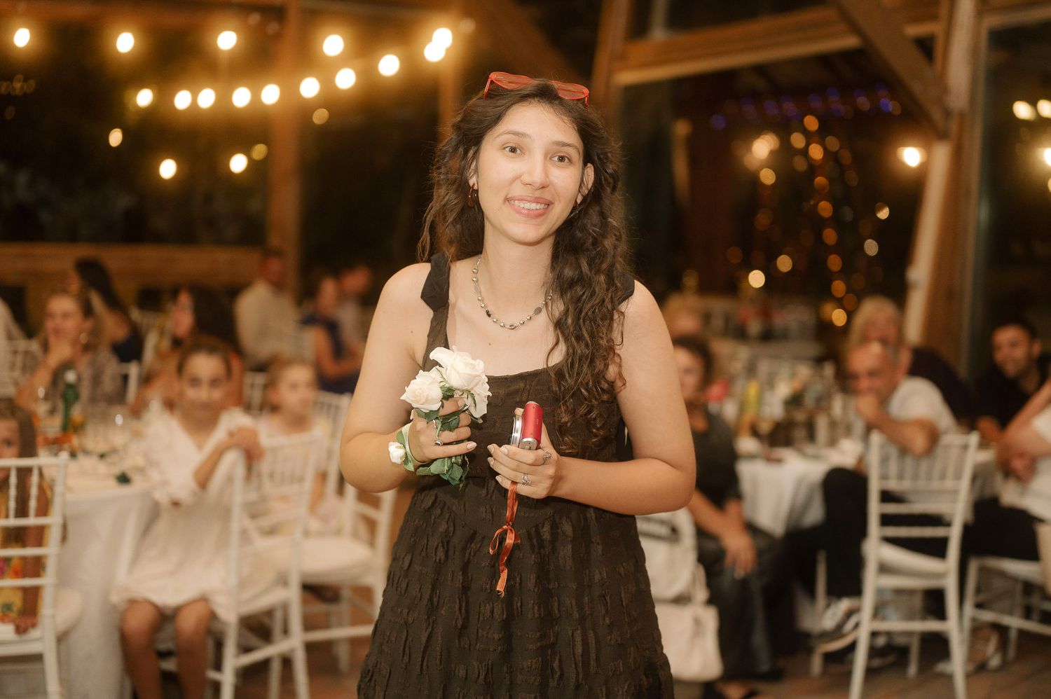 A wedding reception venue decorated with warm string lights and white chairs creating an elegant evening atmosphere.