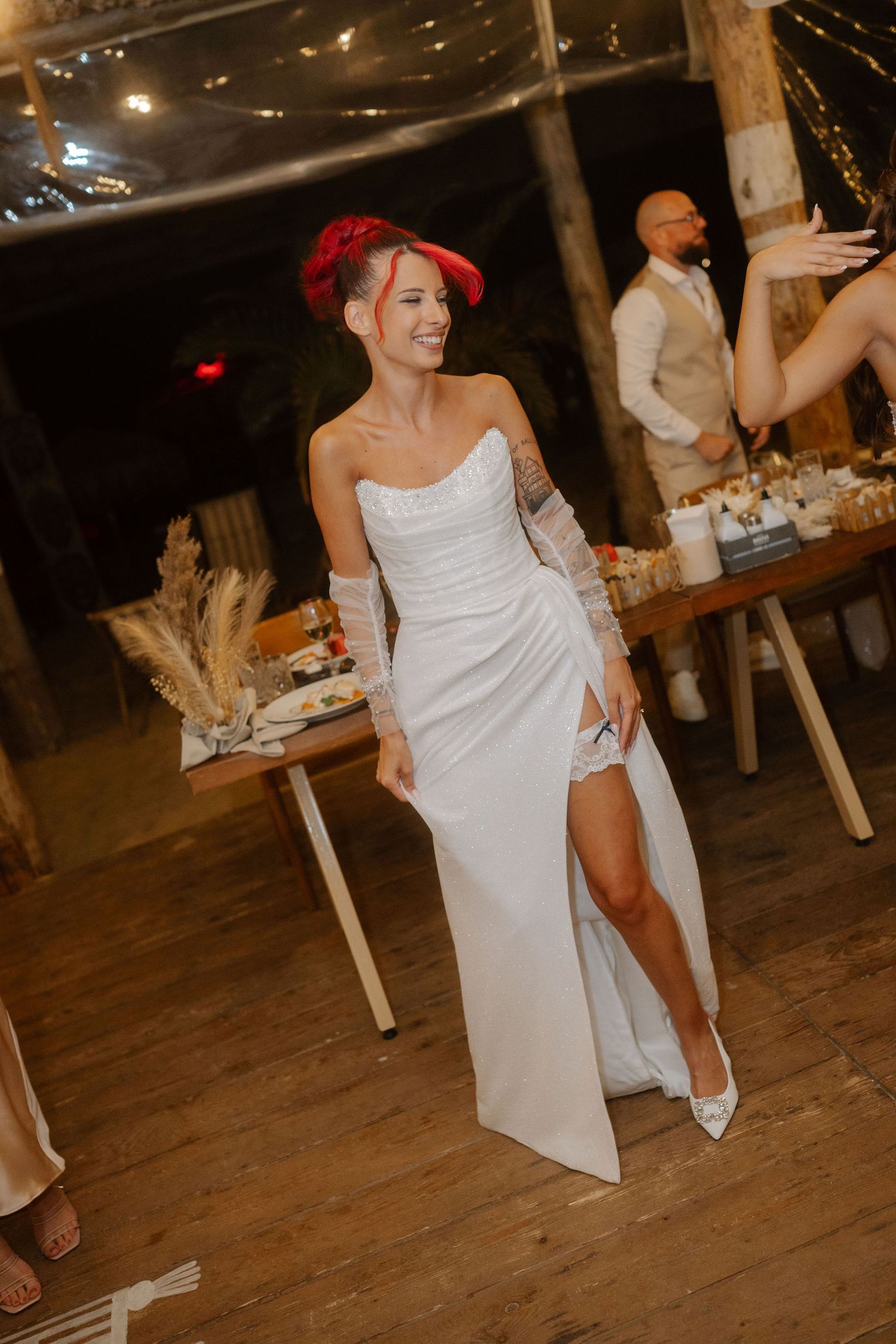 Wedding guests dancing and celebrating on rustic wooden dance floor at evening reception.