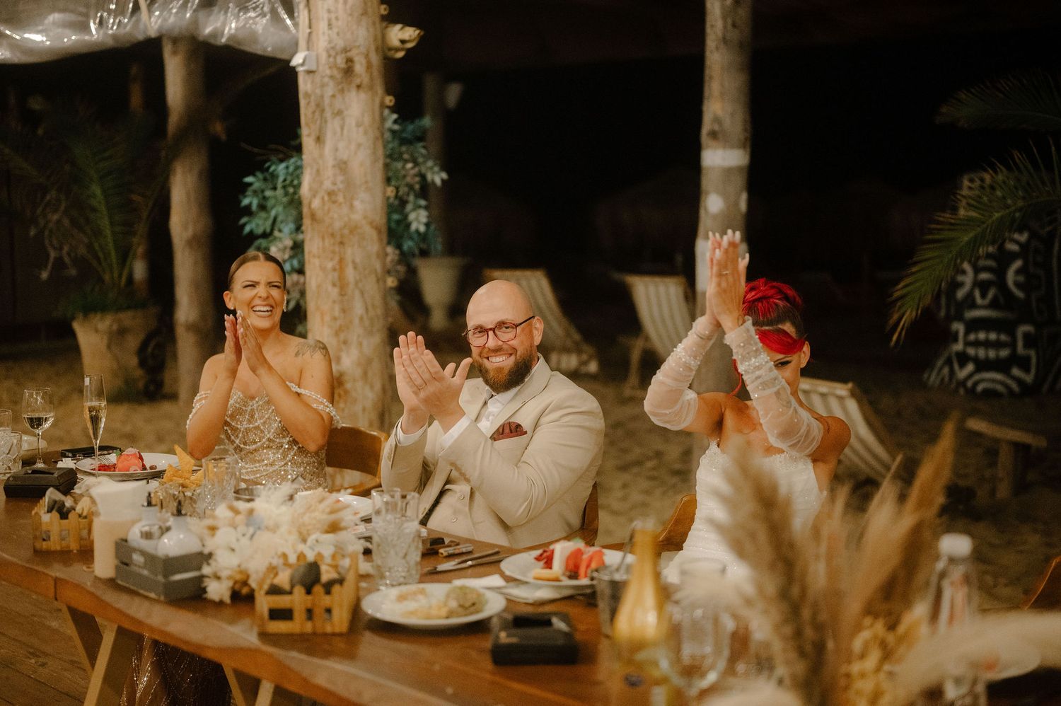 Wedding guests share emotional moments during outdoor reception toasts at sunset.