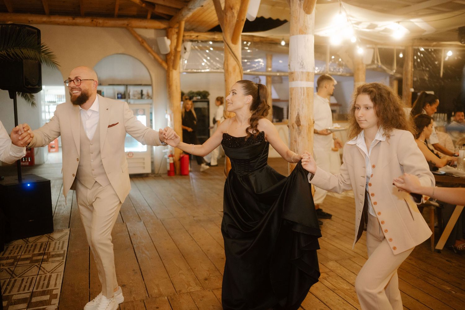 A series of candid dance floor moments at a wedding reception showing guests enjoying themselves in a rustic venue.