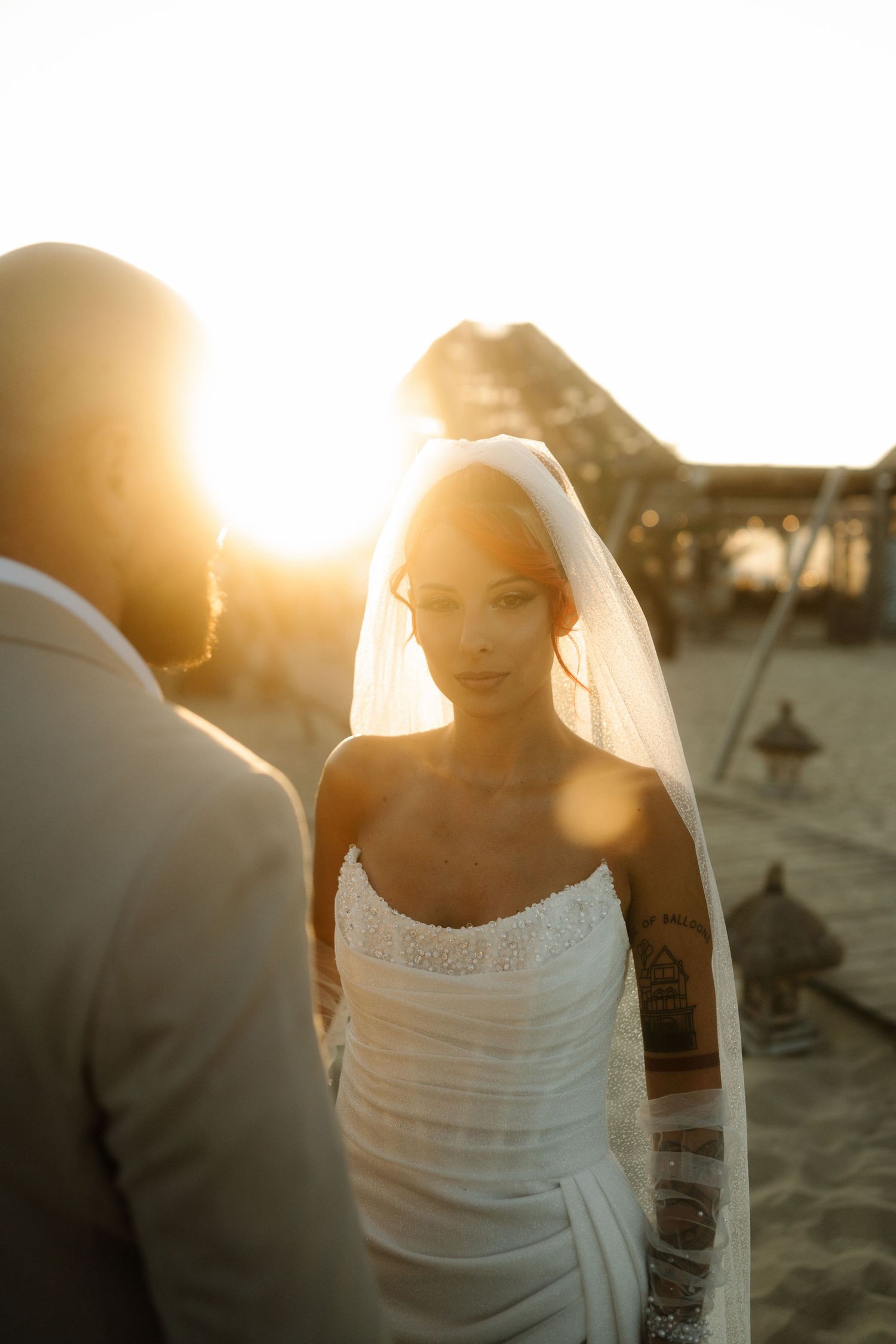 A couple shares an intimate moment on the beach at sunset with golden light illuminating their silhouettes.