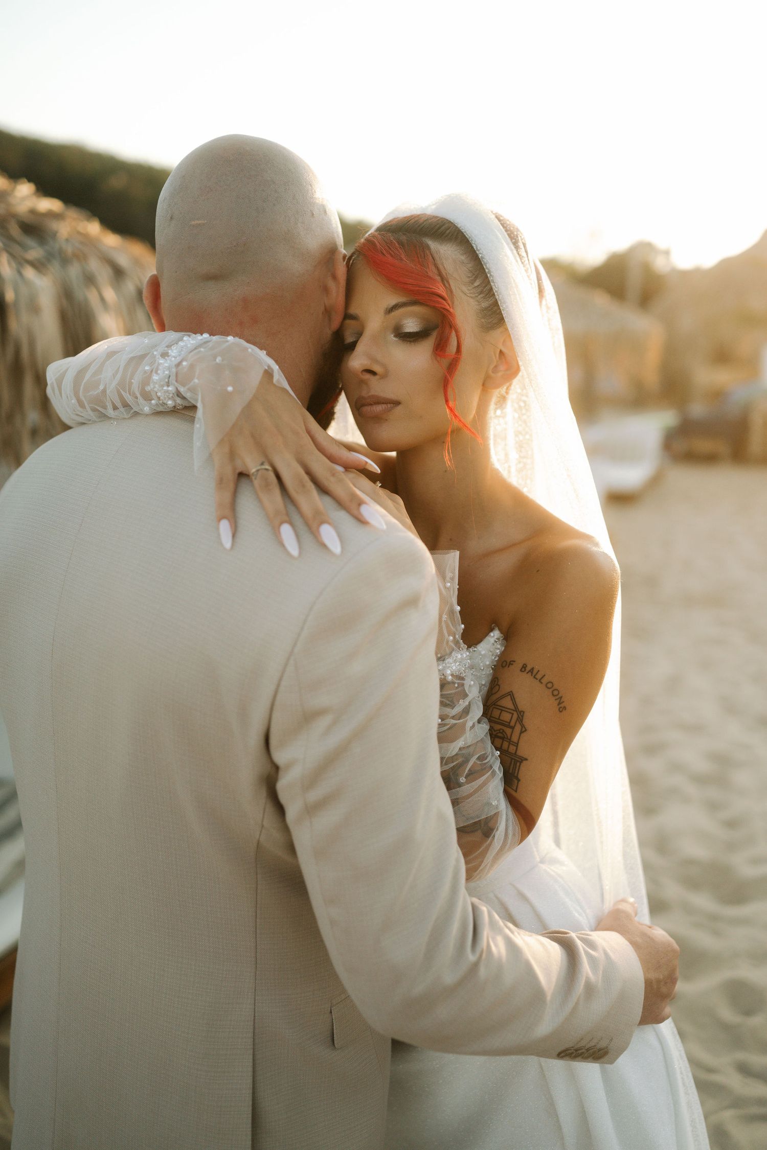 A romantic beach wedding photoshoot at sunset with the couple embracing in soft golden light.