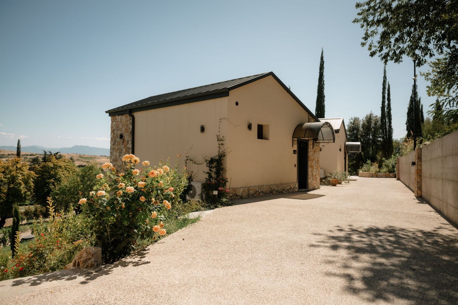 A panoramic sequence showing a winding dirt path leading past tan buildings and trees in a desert landscape.