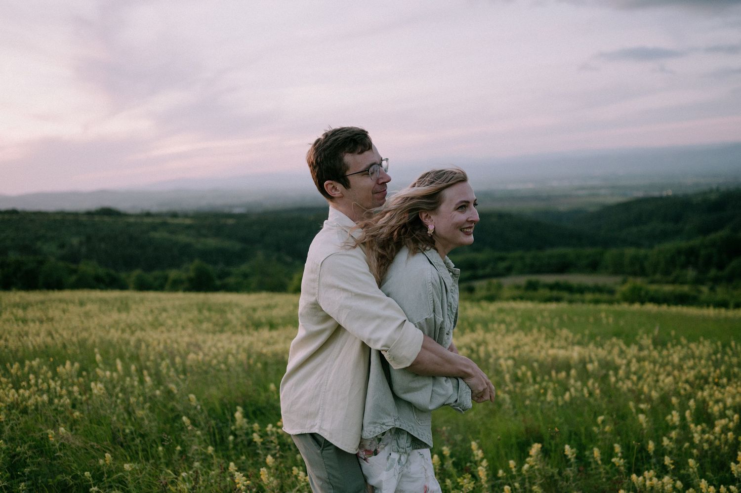Two people share a tender moment while dancing in a mountain meadow at dusk.