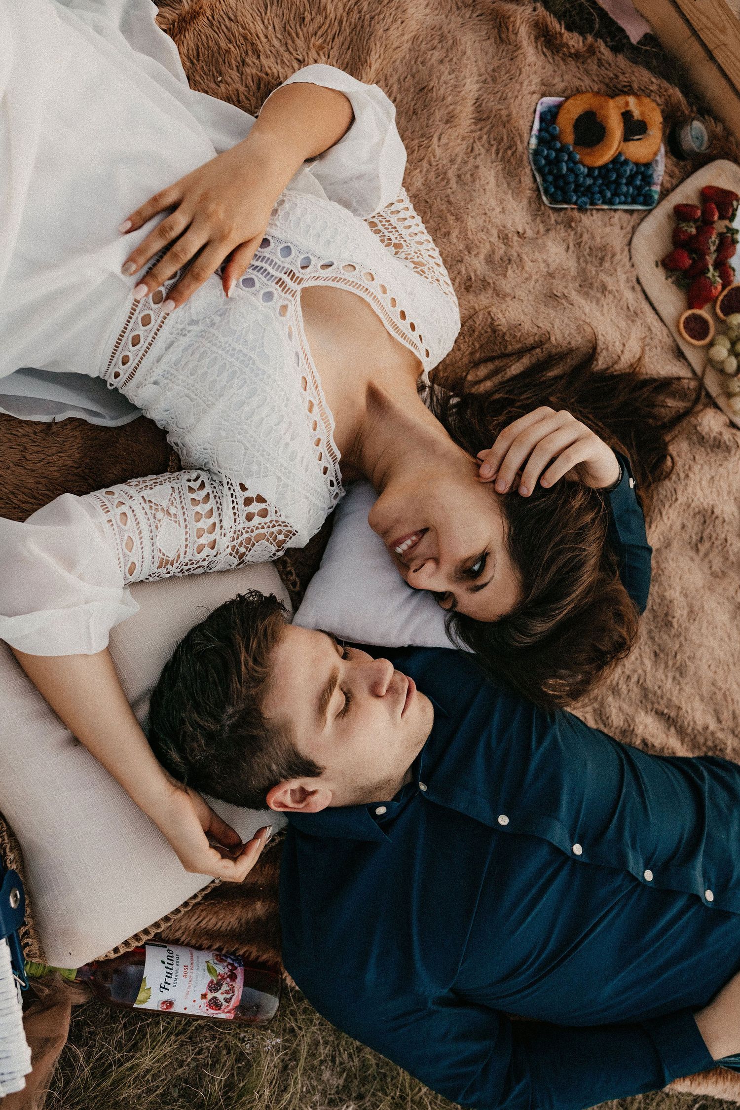 Couple sharing intimate moments on a blanket during sunset picnic.