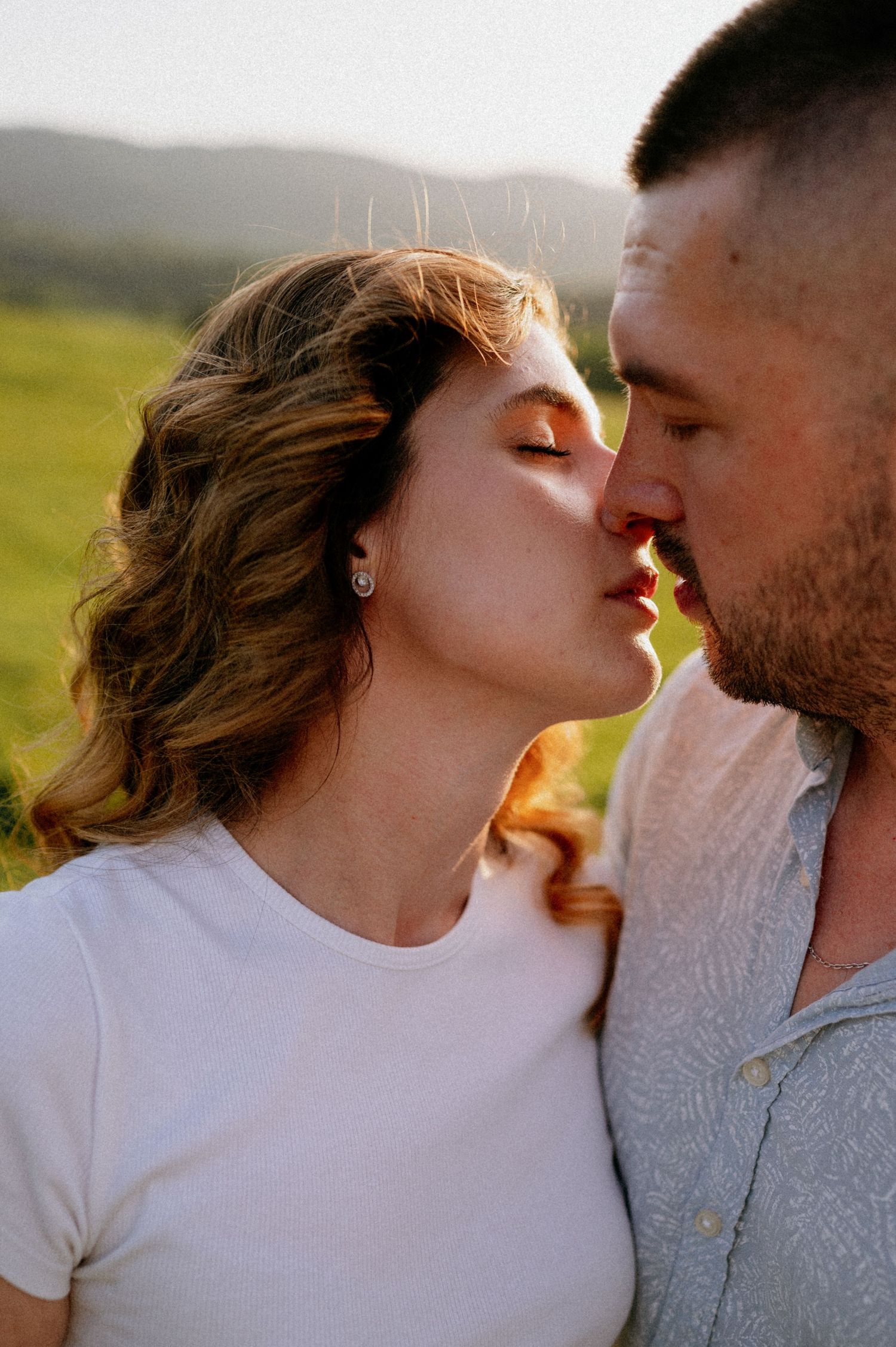 Romantic couple sharing an intimate moment in a sunlit meadow during golden hour.