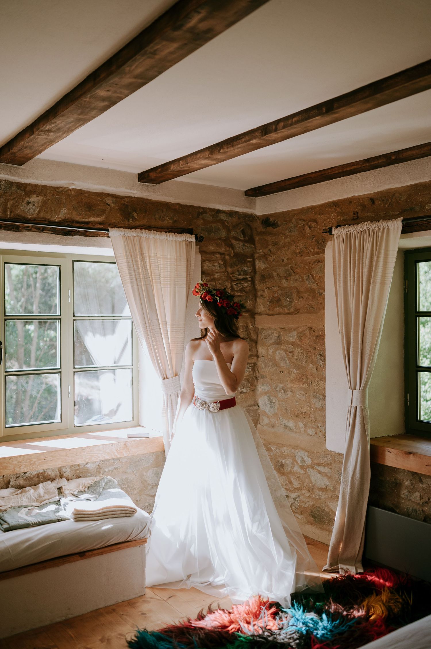 Elegant bridal portrait in stone room with exposed wooden beams and flowing curtains.