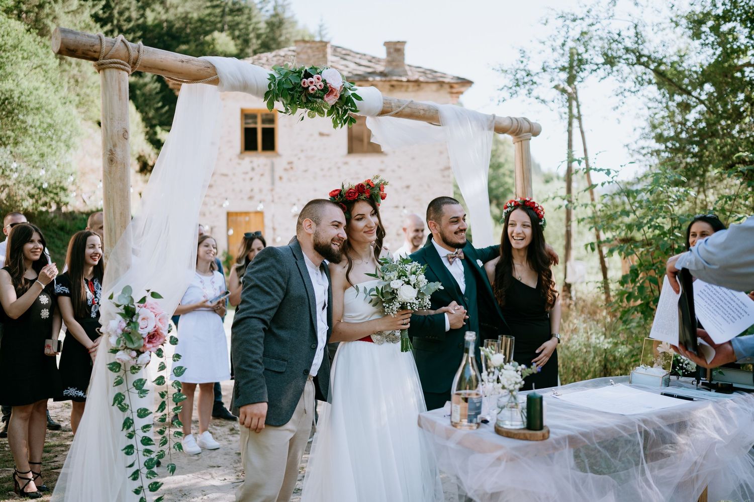 Elegant outdoor wedding reception with guests gathered around decorative white floral arrangements.