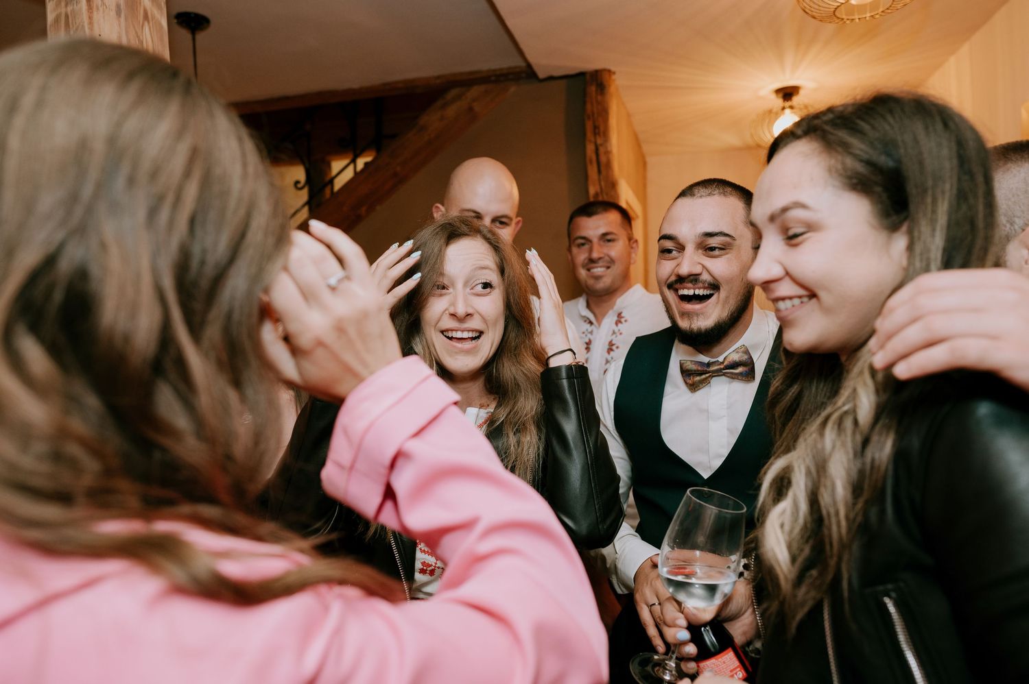 Joyful party guests sharing laughs and drinks at an indoor celebration.