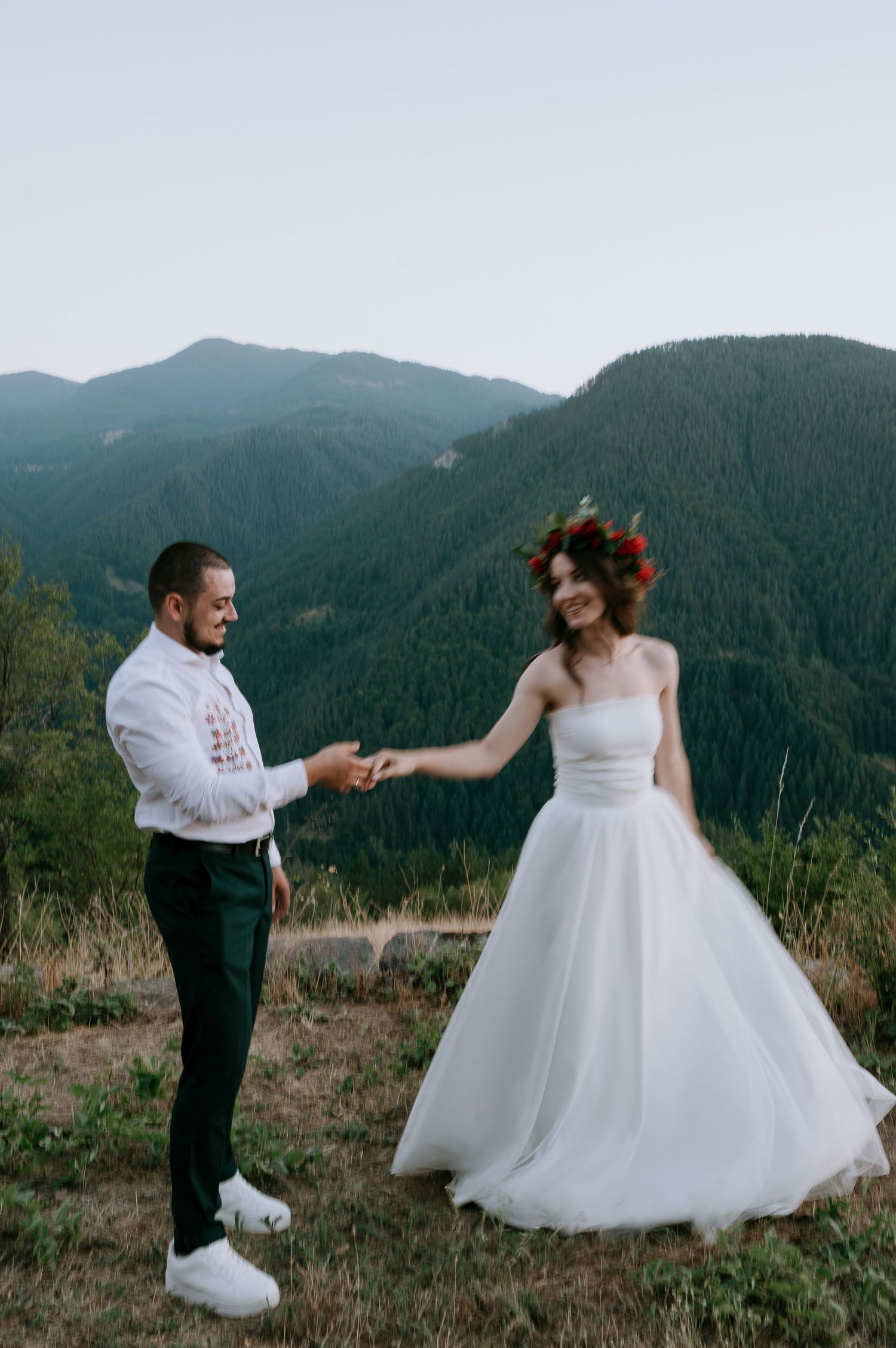 A couple dances together against a backdrop of mountain scenery during their wedding photoshoot.