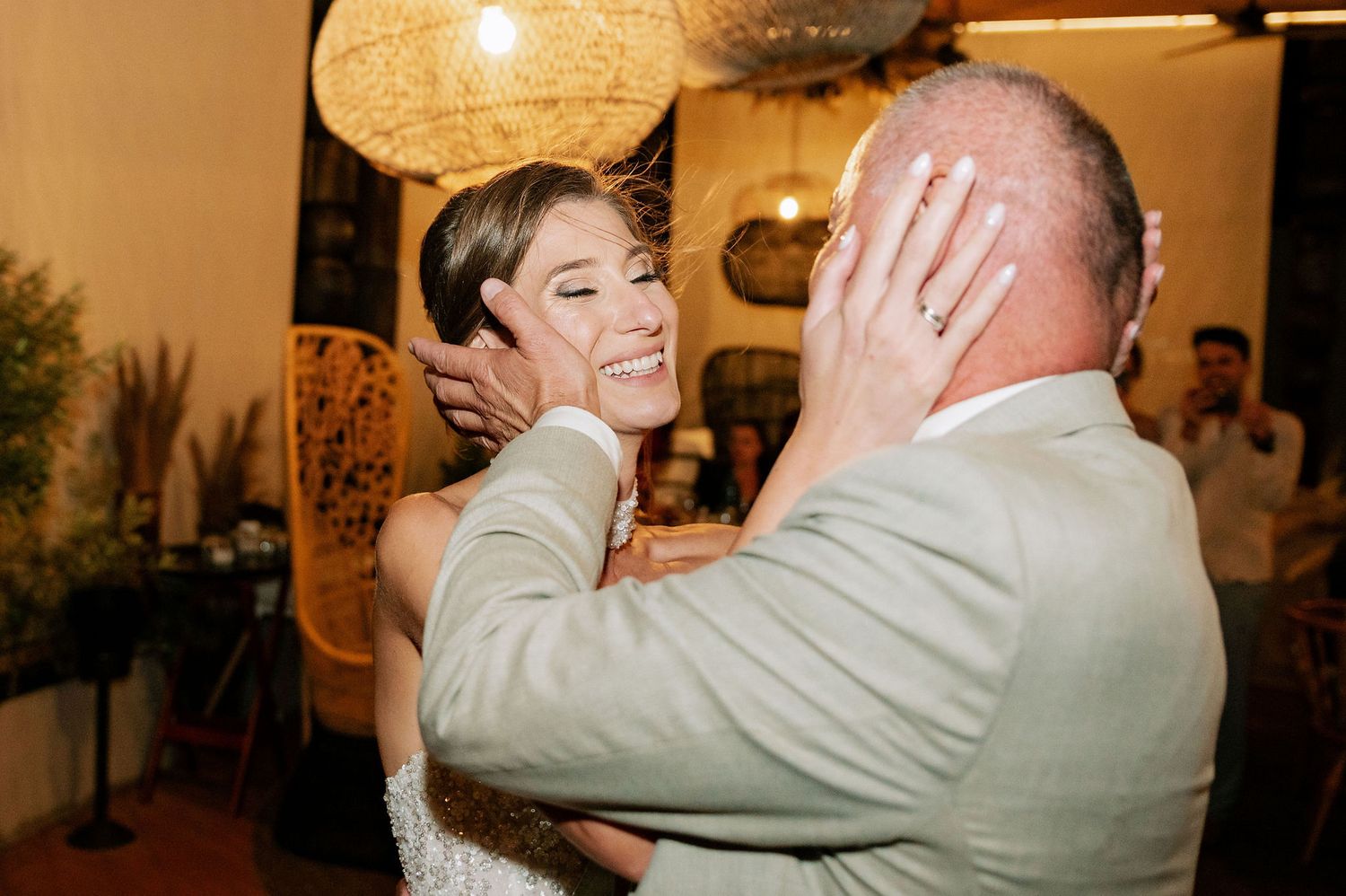 Wedding reception dance floor moment captured under glowing pendant lights.