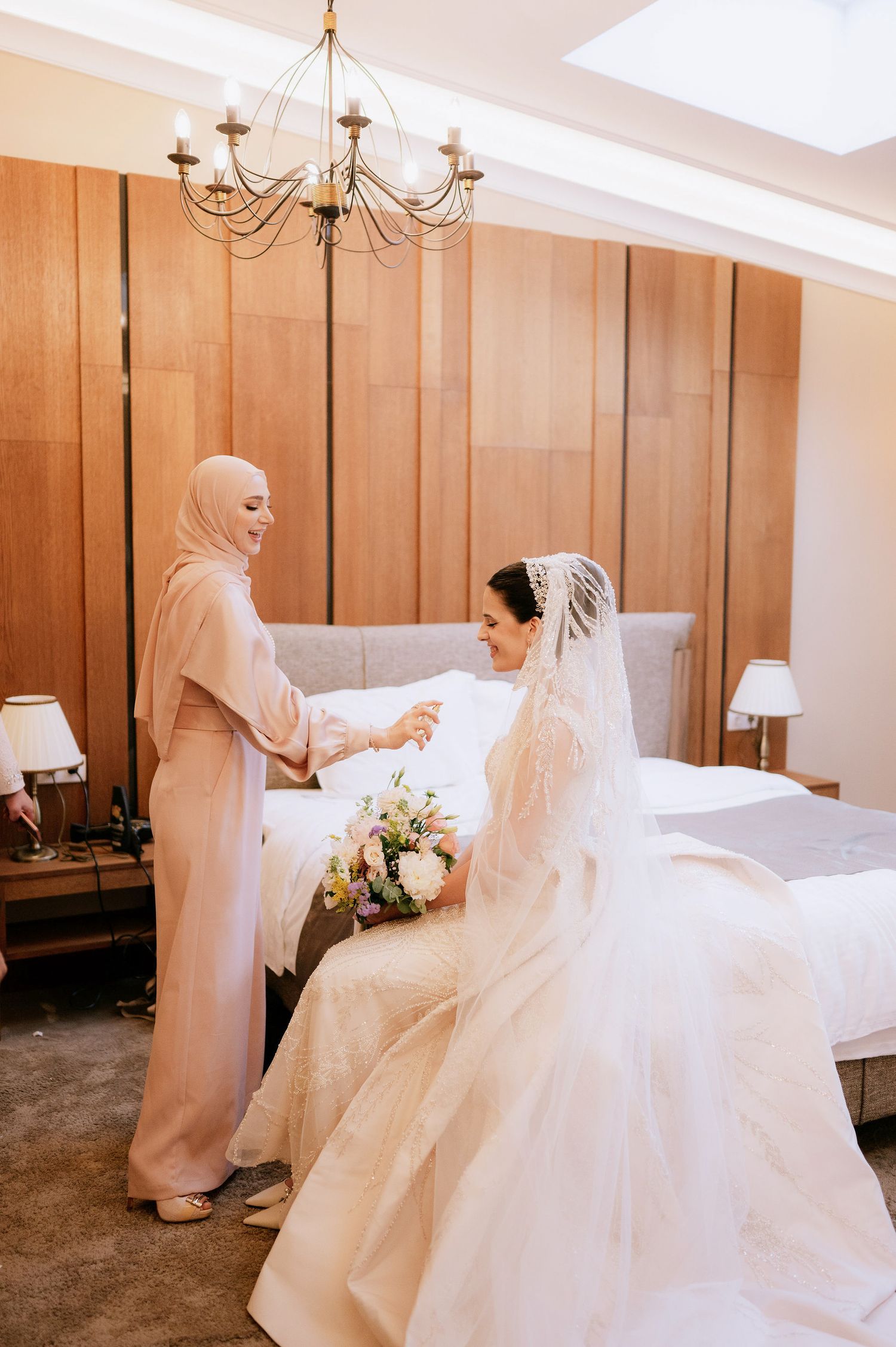 A bride in an elegant white gown poses in a room with warm wooden wall panels.