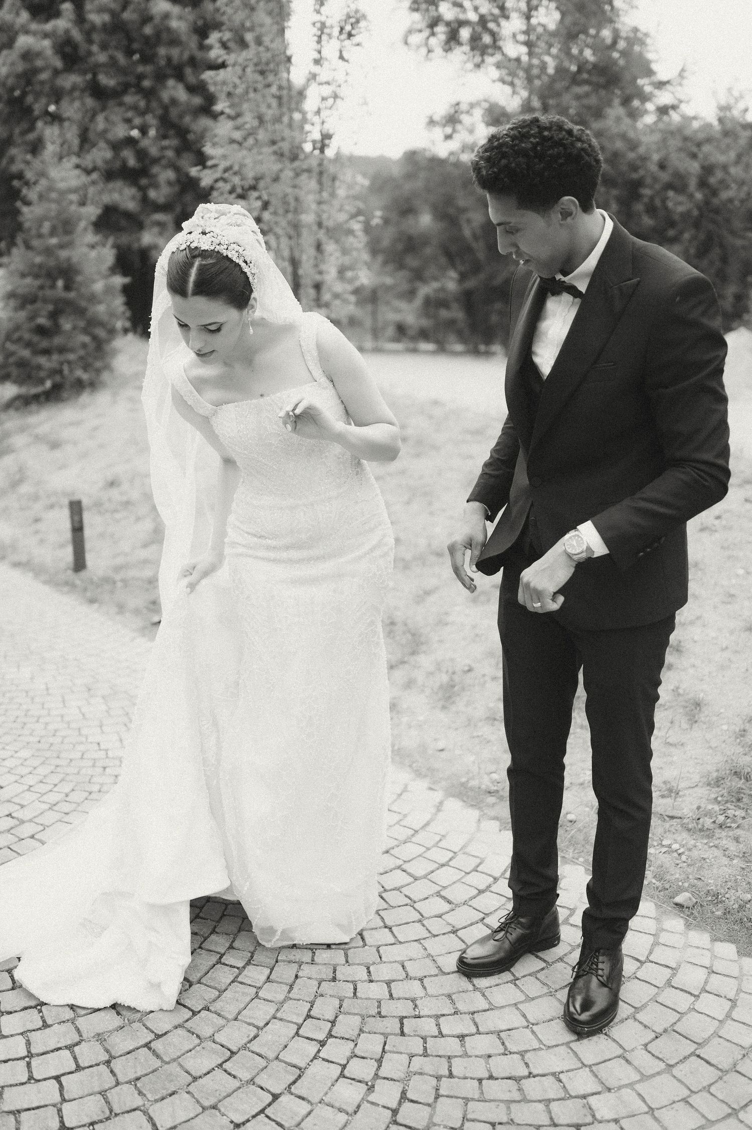 Black and white wedding photos showing a couple's playful interaction on a cobblestone walkway.