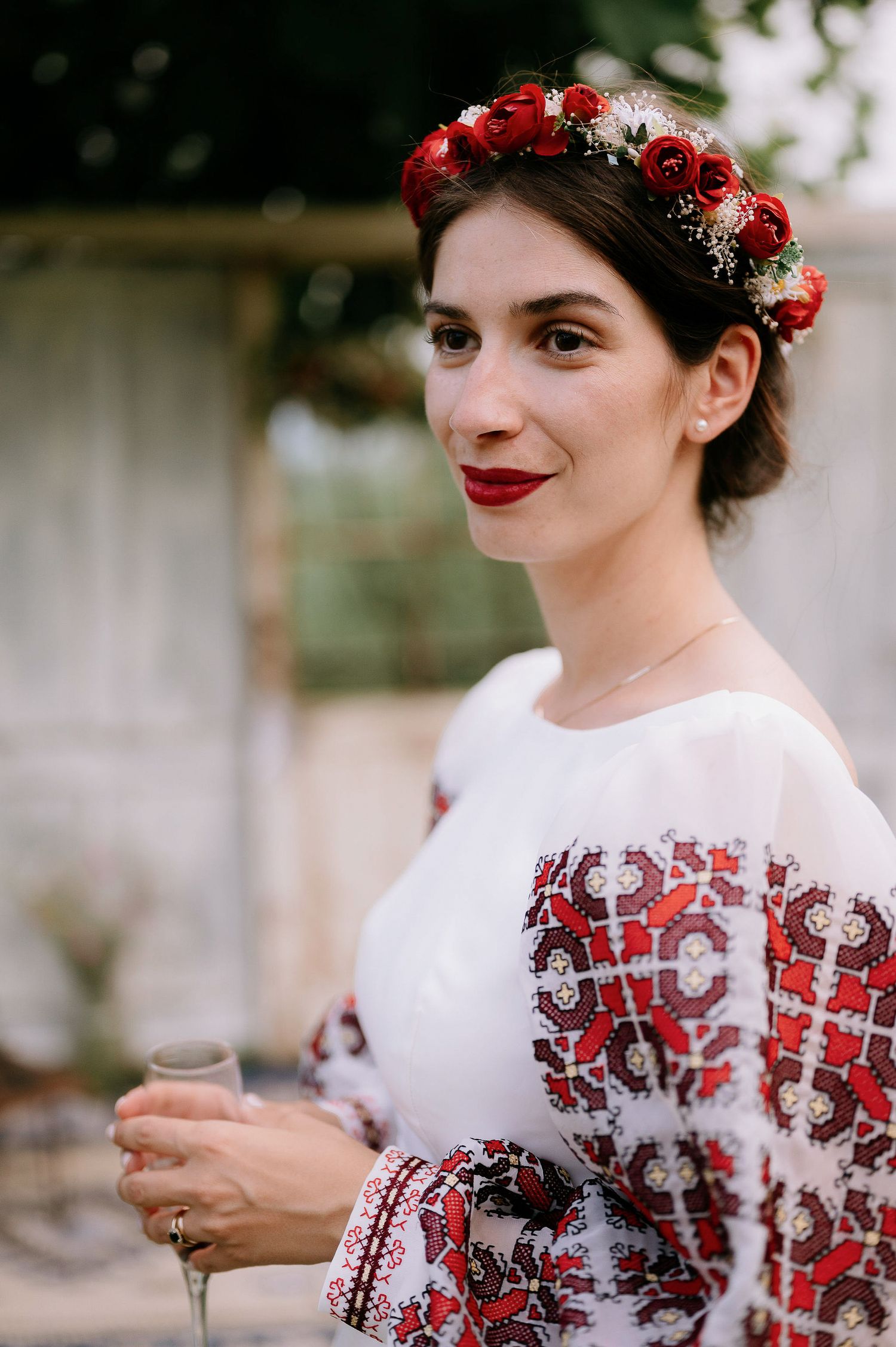Portrait with red rose crown and white embroidered dress with red details.