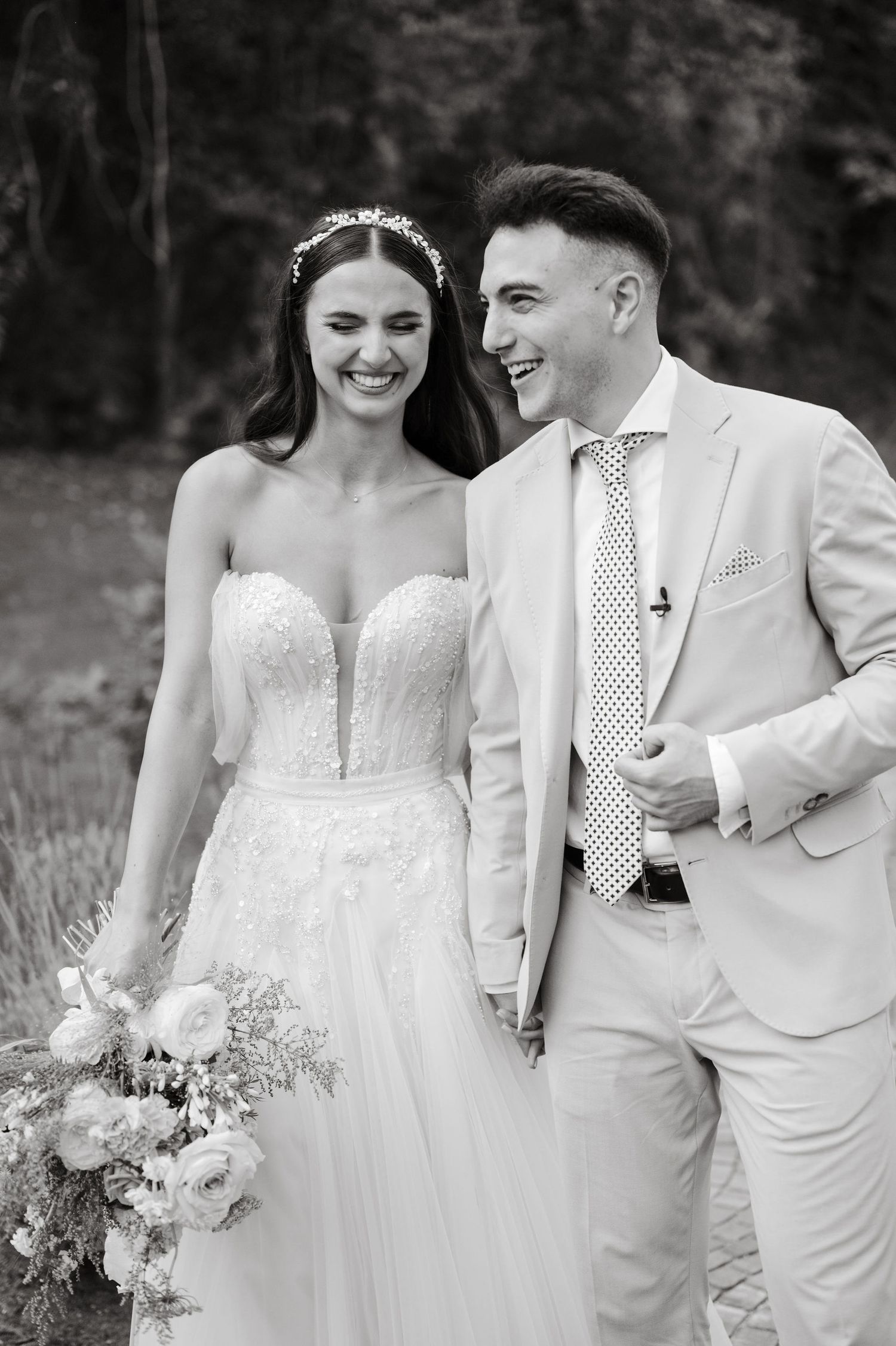 Black and white wedding portrait showing couple sharing joyful moment outdoors.