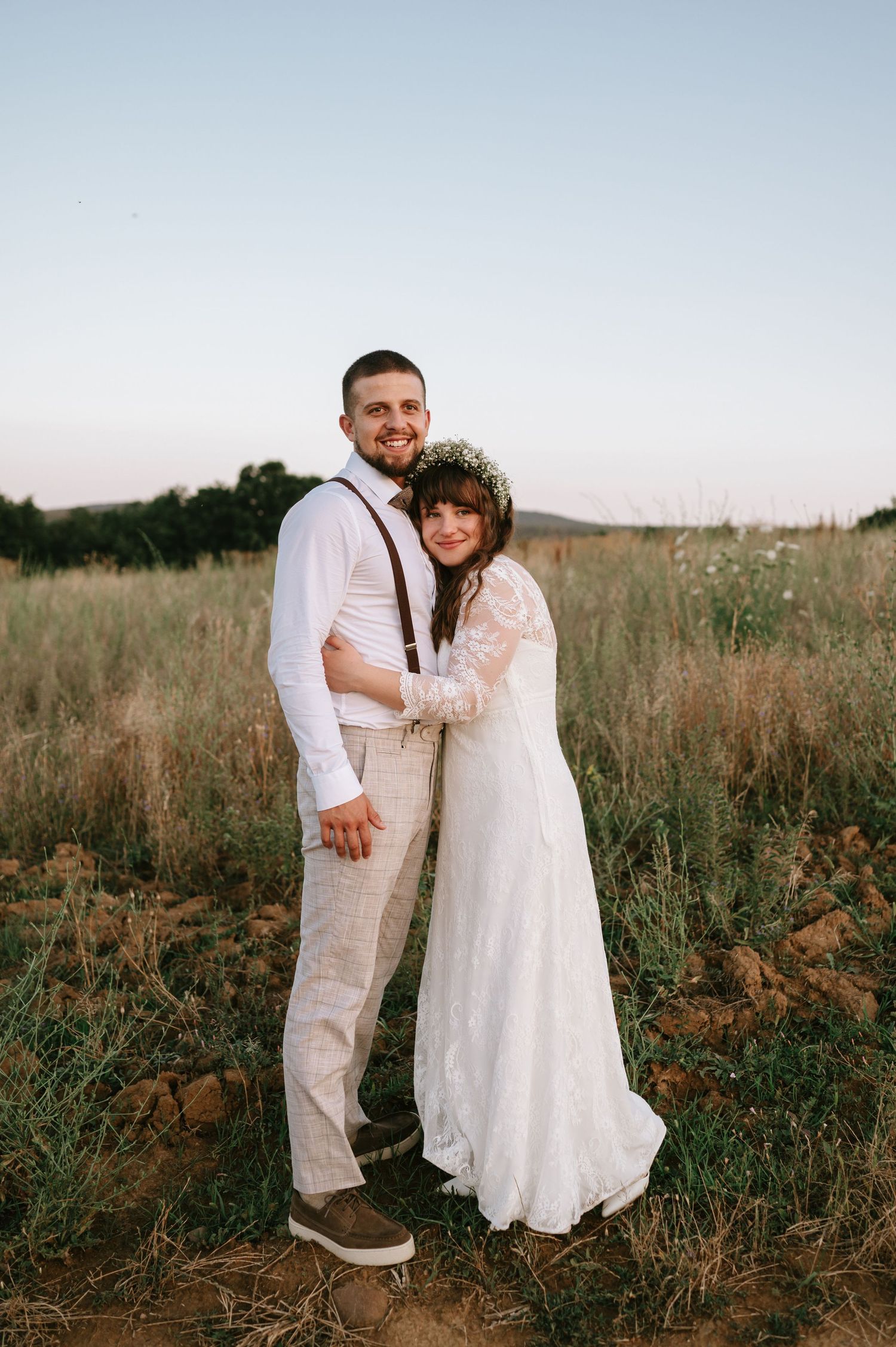 A couple embraces in a golden field during their wedding photoshoot.