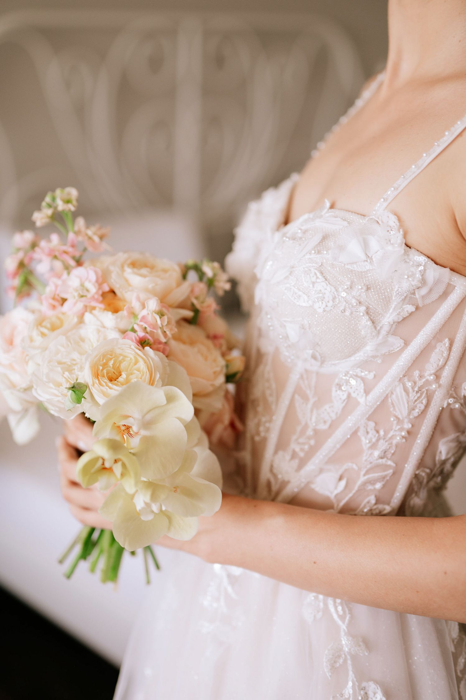 Close-up details of a white lace wedding dress with delicate floral bouquet accents.