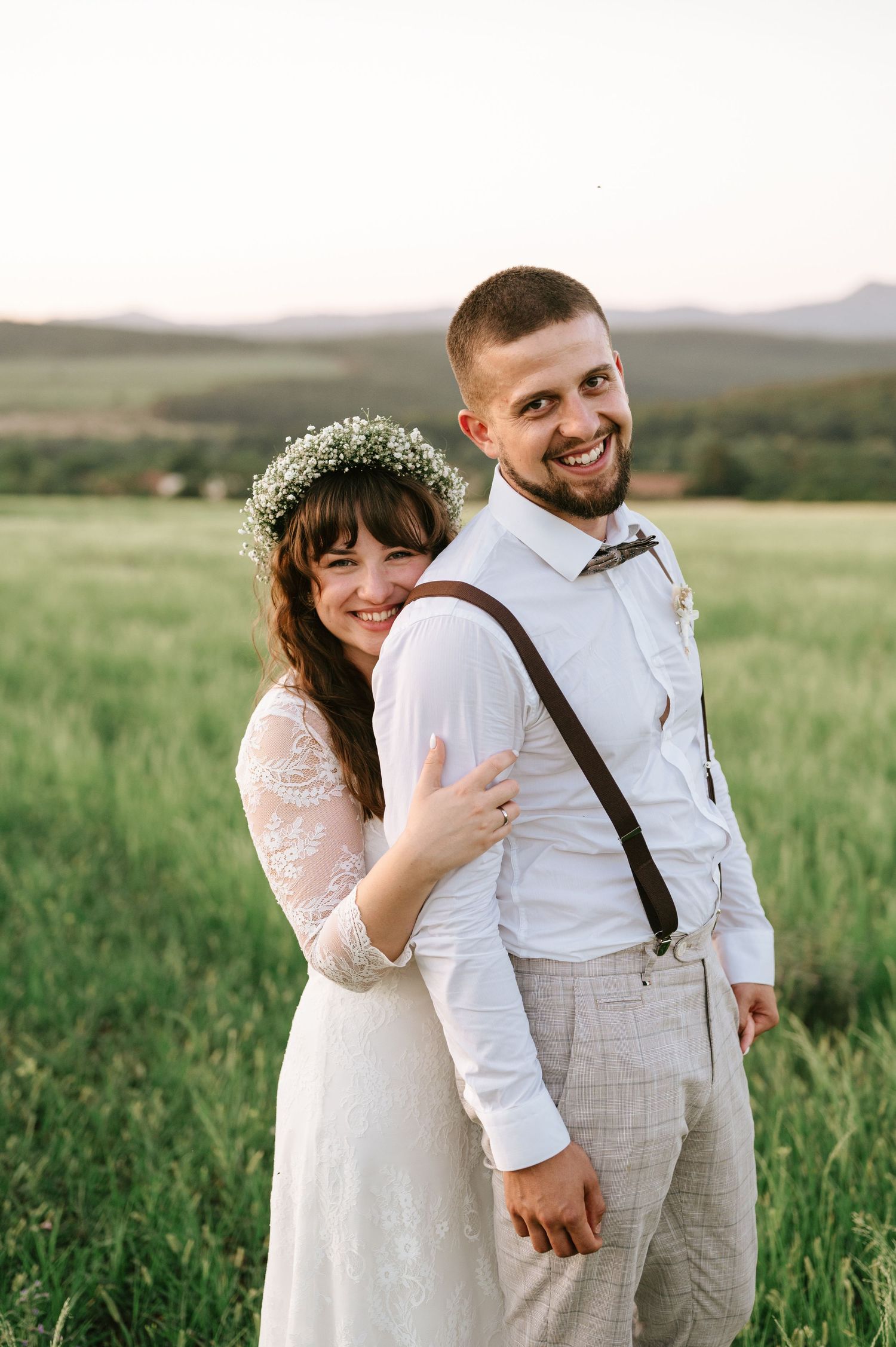 A happy couple shares a candid moment in their wedding attire against a mountain backdrop.