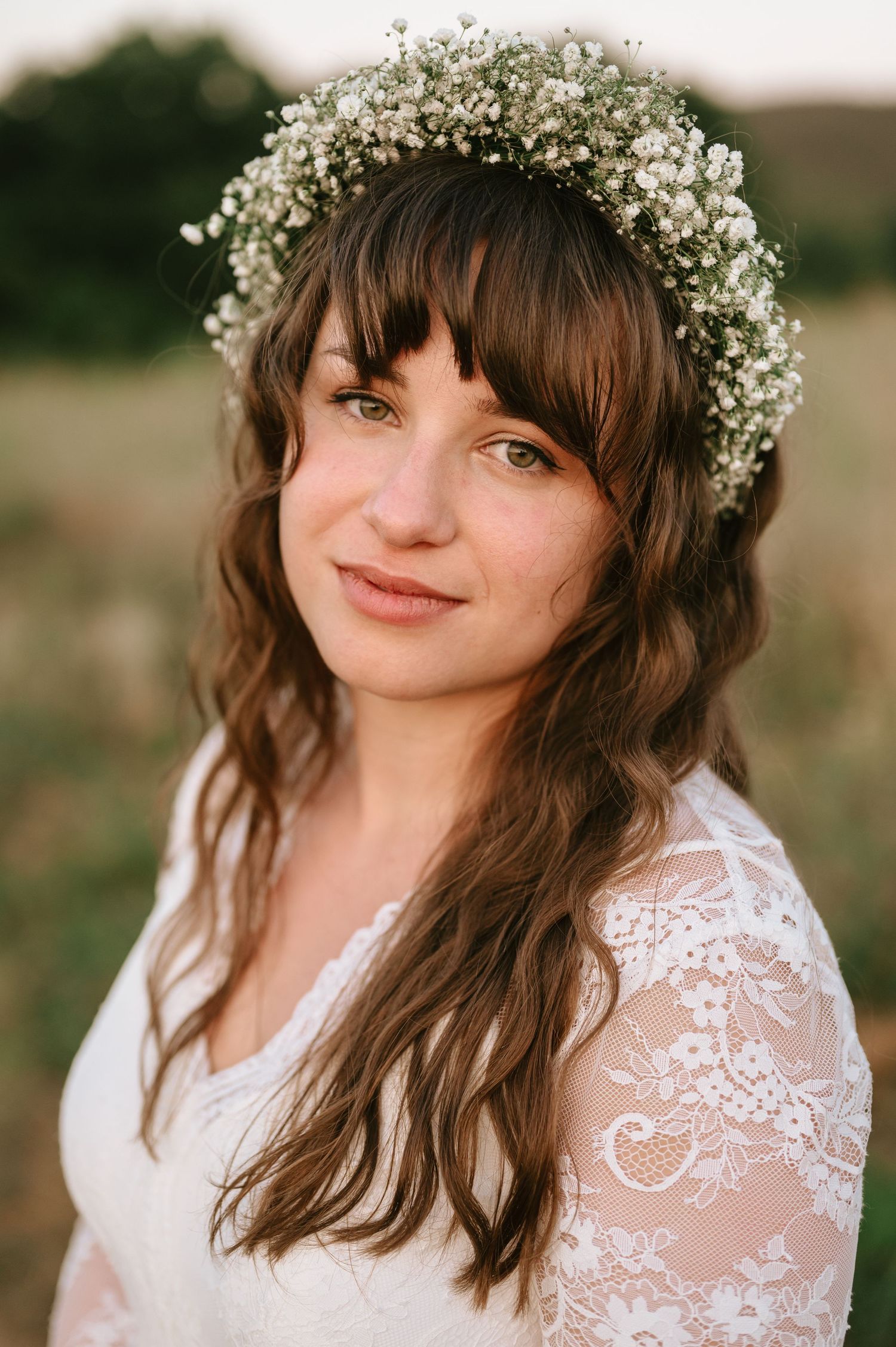 Delicate lace dress and baby's breath crown complement natural outdoor wedding portrait.