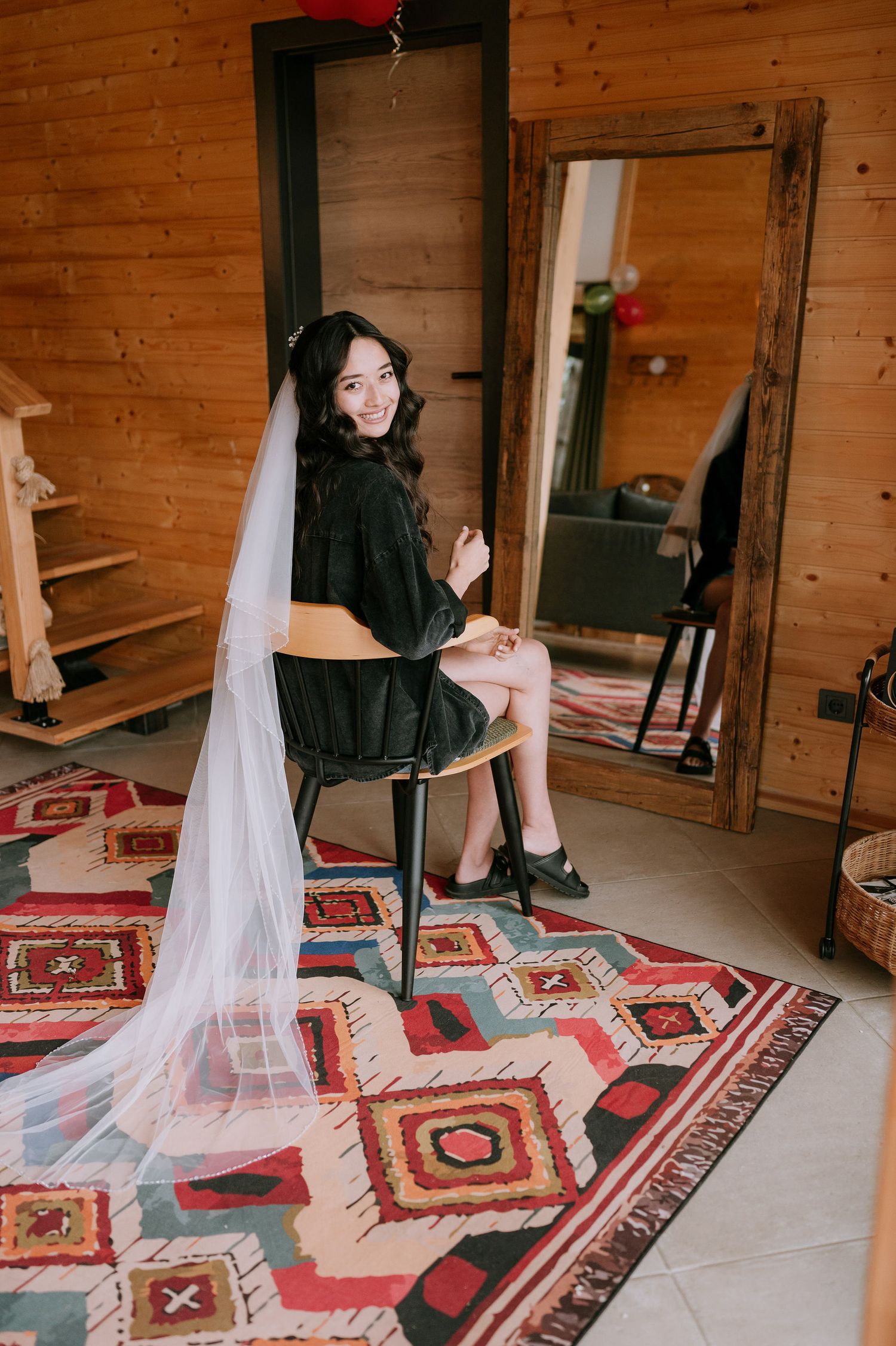 Artistic bridal boudoir photo with dramatic veil placement on patterned rug.