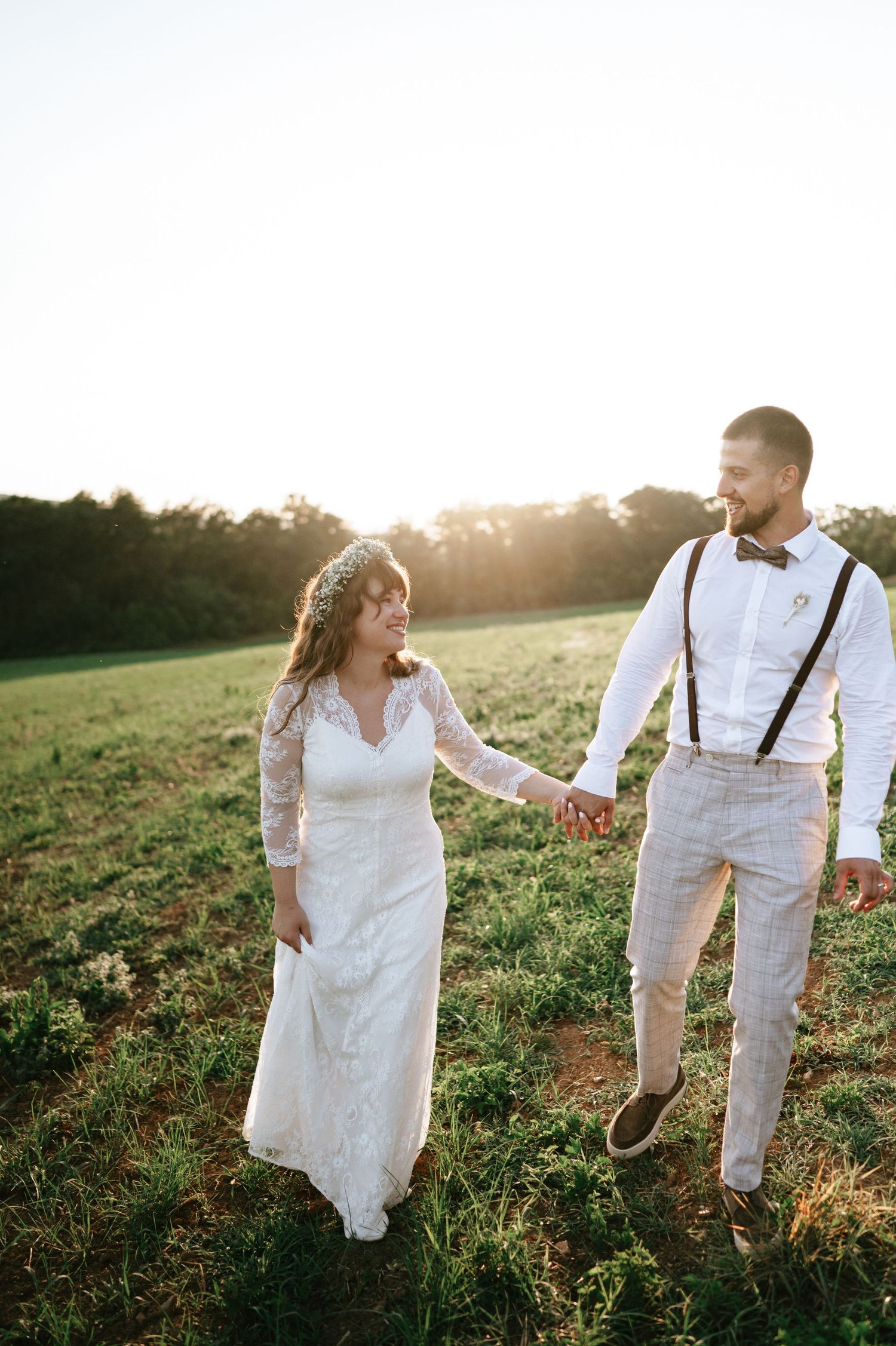 Wedding couple shares a romantic moment in a meadow during sunset photography session.