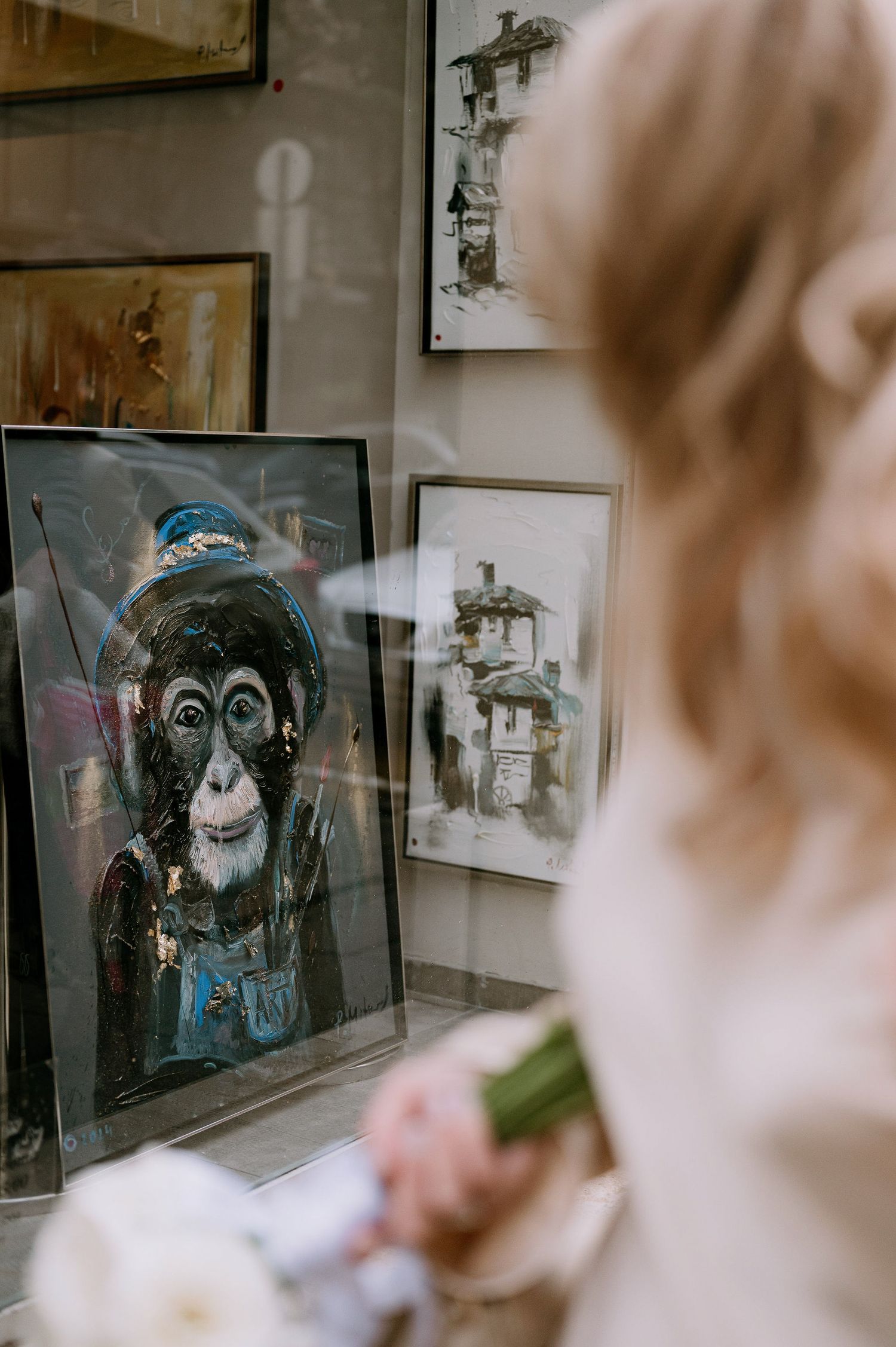 Blurred view through gallery window showing artwork displays.