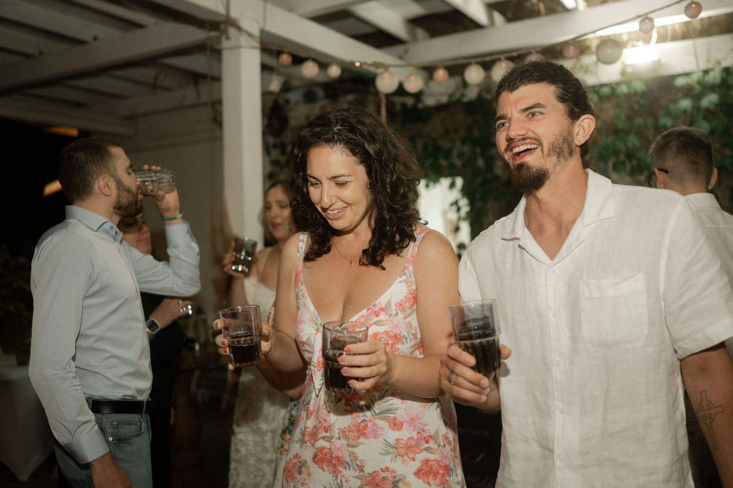 A group of wedding guests dance and celebrate together at a reception in an indoor venue.