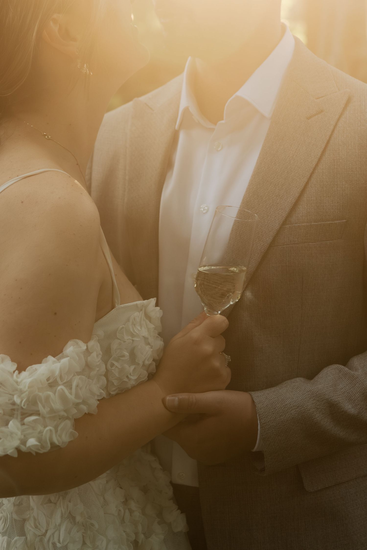 A romantic golden hour wedding portrait with a couple in formal attire illuminated by warm sunlight.
