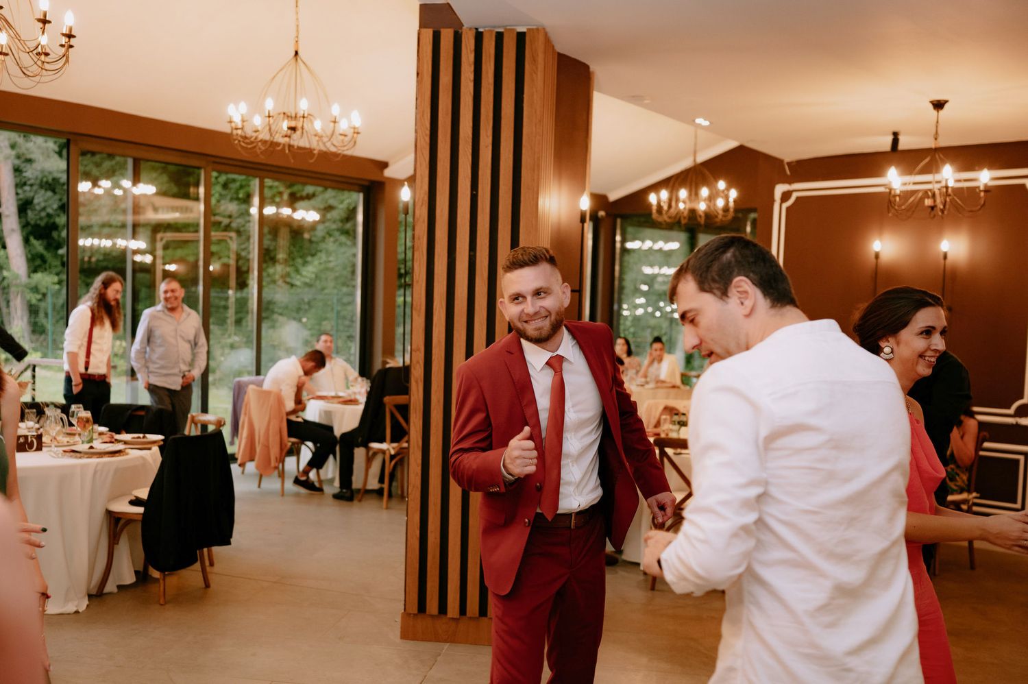 Guests dance and celebrate at an elegant indoor wedding reception with warm lighting and wooden accents.
